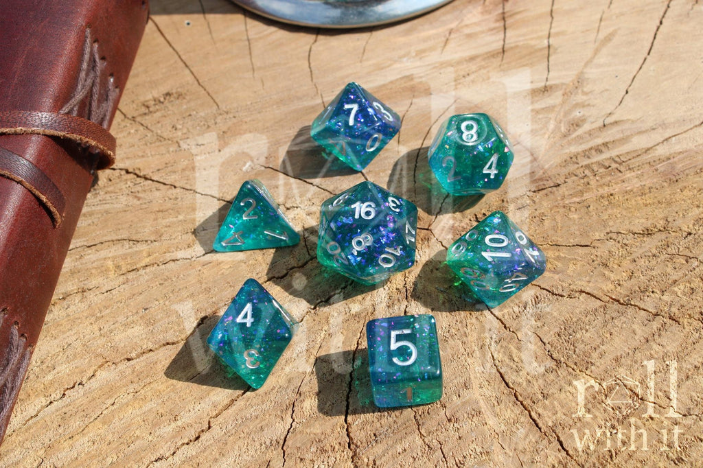 Set of glittery and shining blue and green polyhedral DND dice with silver leaf inside on a wooden surface