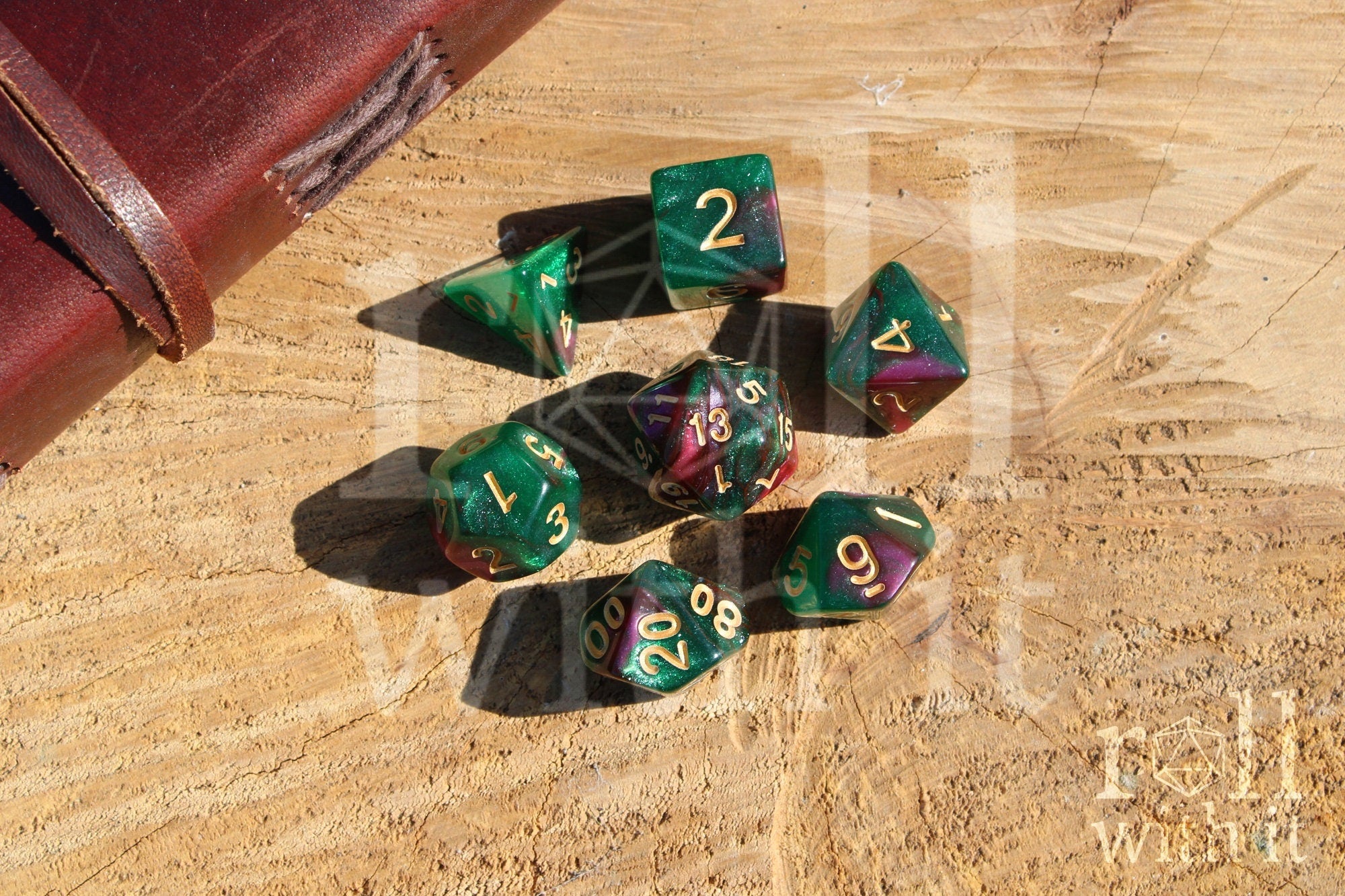 Set of glittery and shimmering green and purple polyhedral dice with gold numbers on a wooden surface