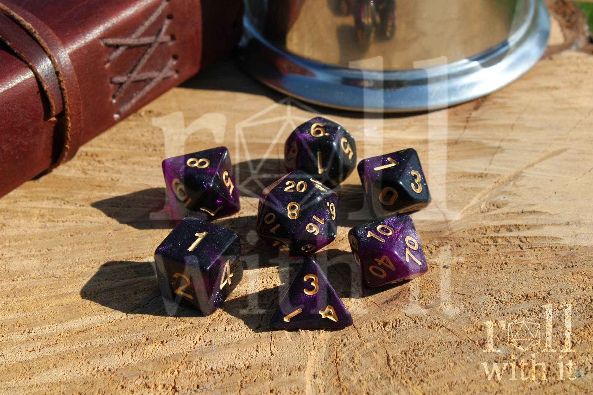 Purple and black glittery polyhedral dice set with gold numbers on a wooden surface