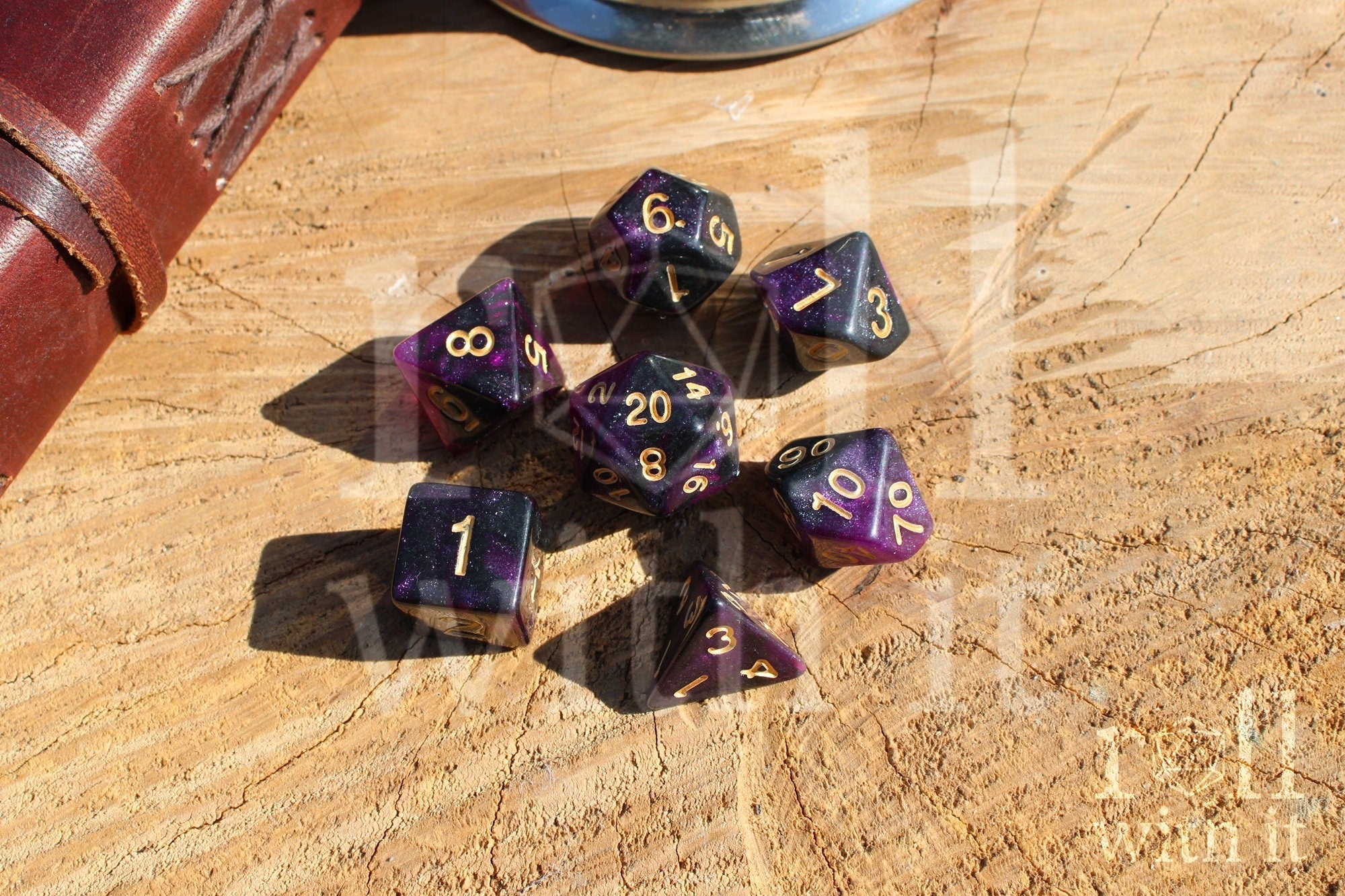 Purple and black glittery polyhedral dice set with gold numbers on a wooden surface