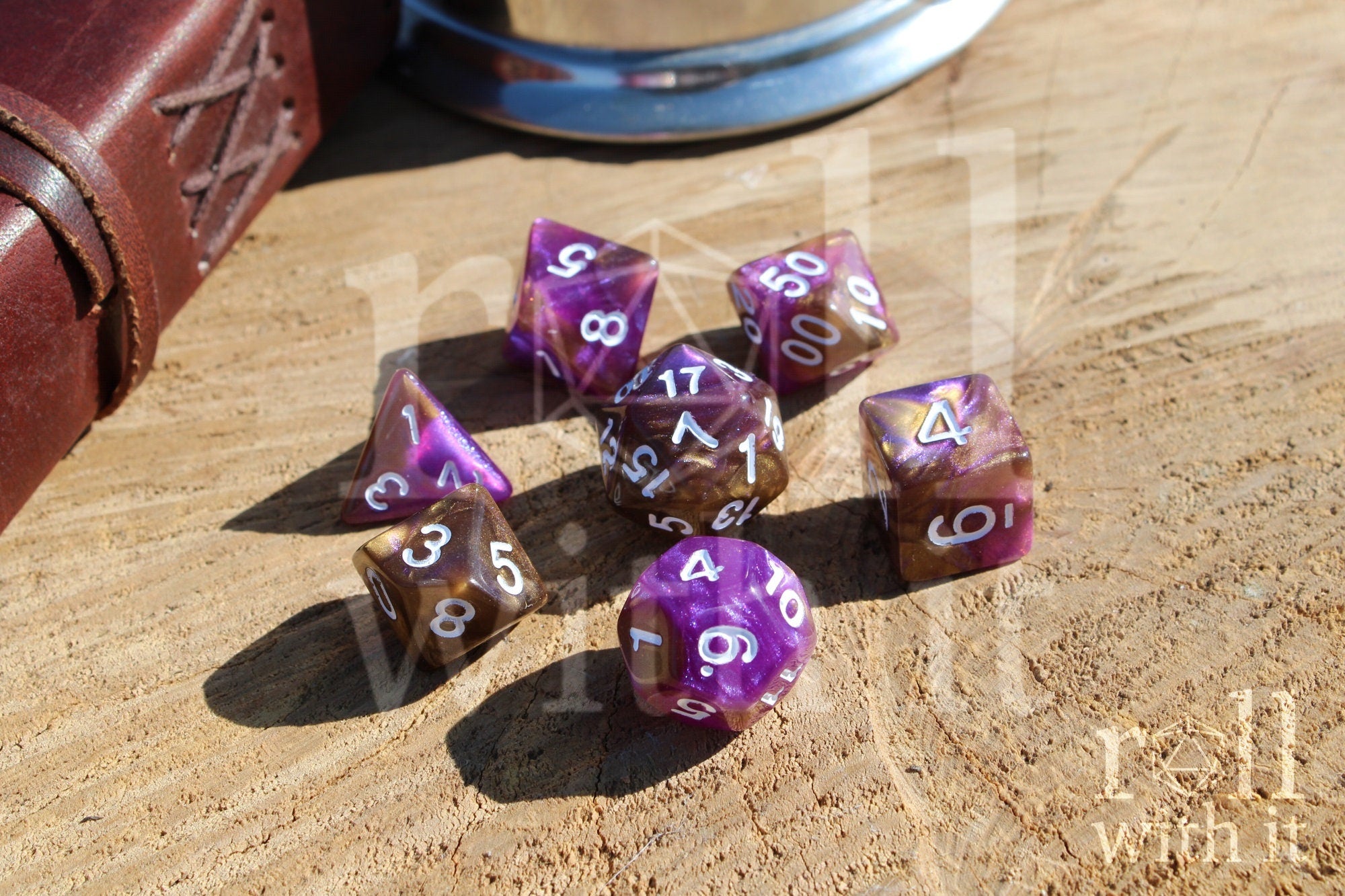 Purple and gold polyhedral roleplaying dice with white numbers on a wooden surface