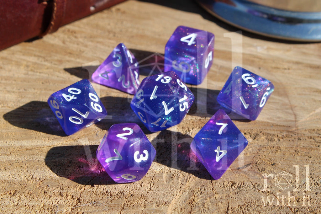 Set of glittery indigo purple polyhedral roleplaying dice with white numbers on a wooden surface