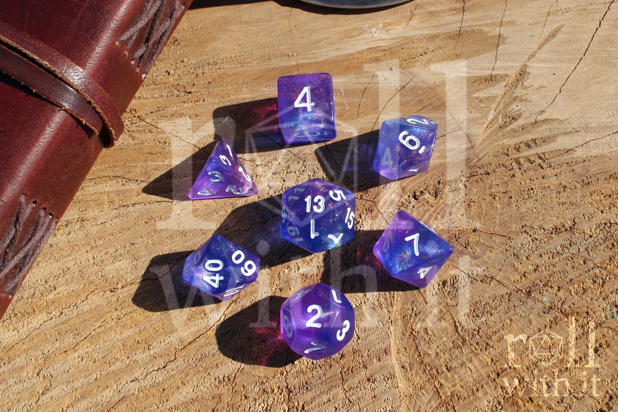 Set of glittery indigo purple polyhedral roleplaying dice with white numbers on a wooden surface