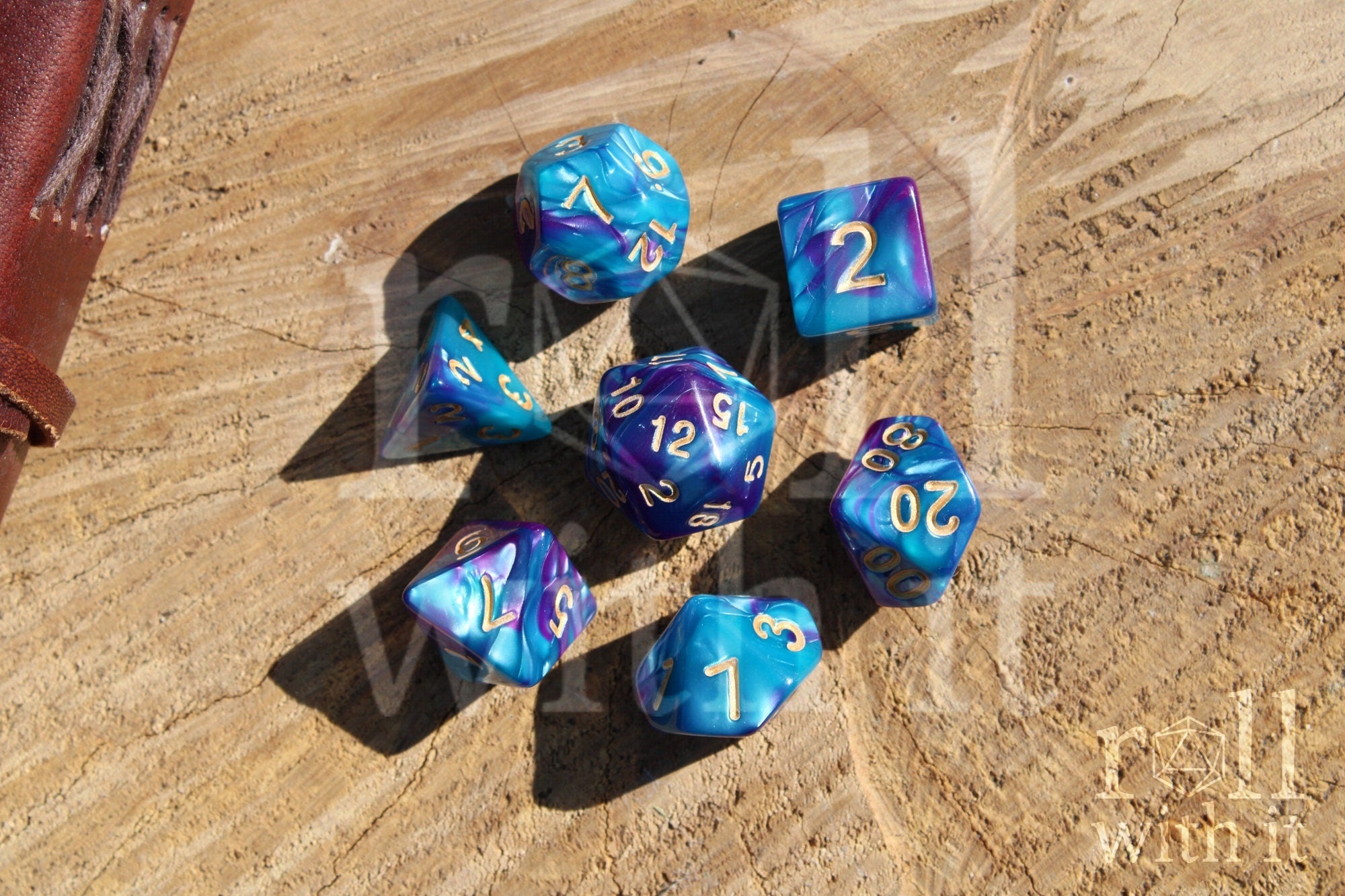 A set of colorful purple and blue polyhedral dice with golden numbers on a wooden surface