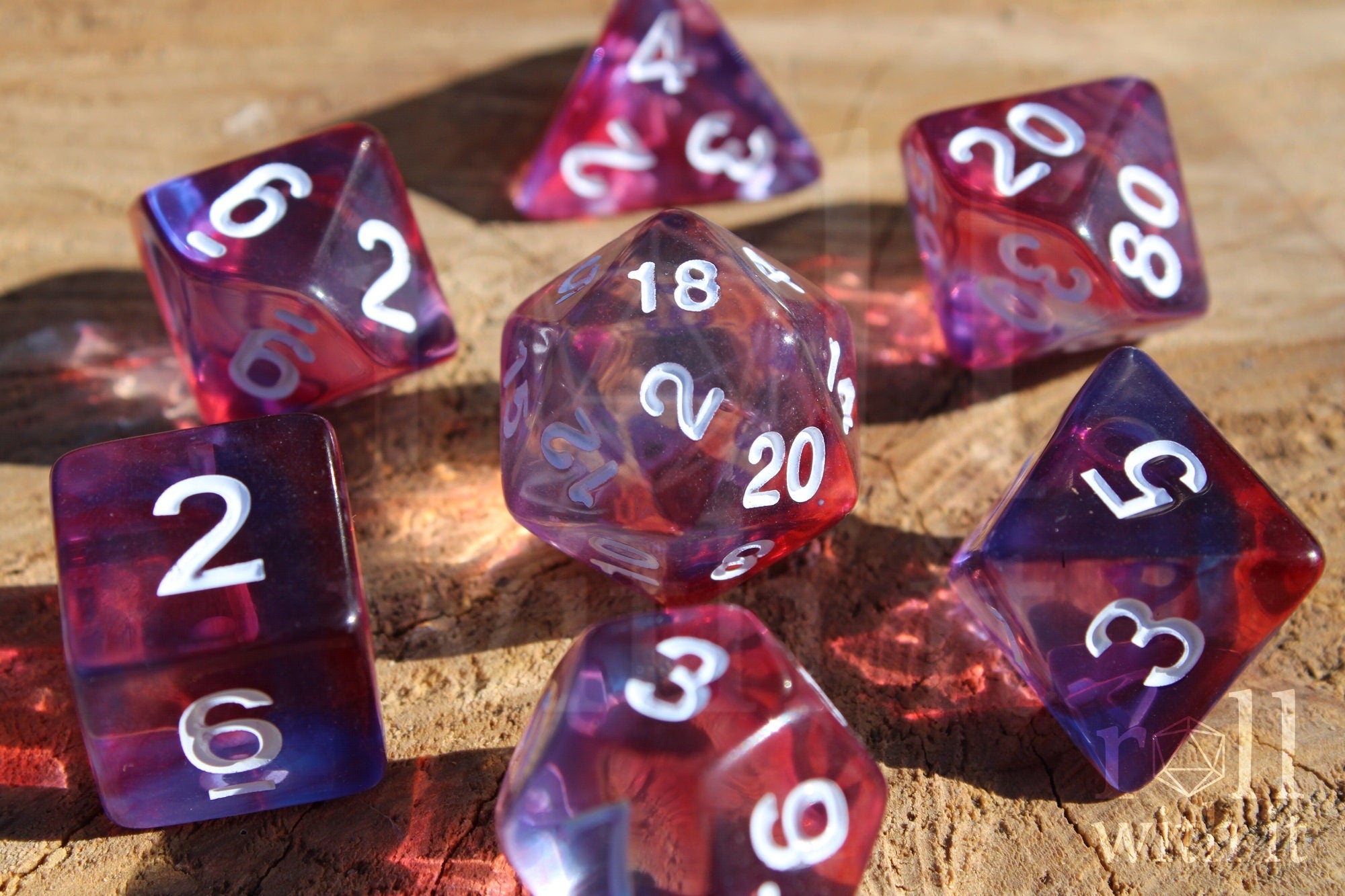 Set of clear purple and red DnD roleplaying dice with white numbers on a wooden surface