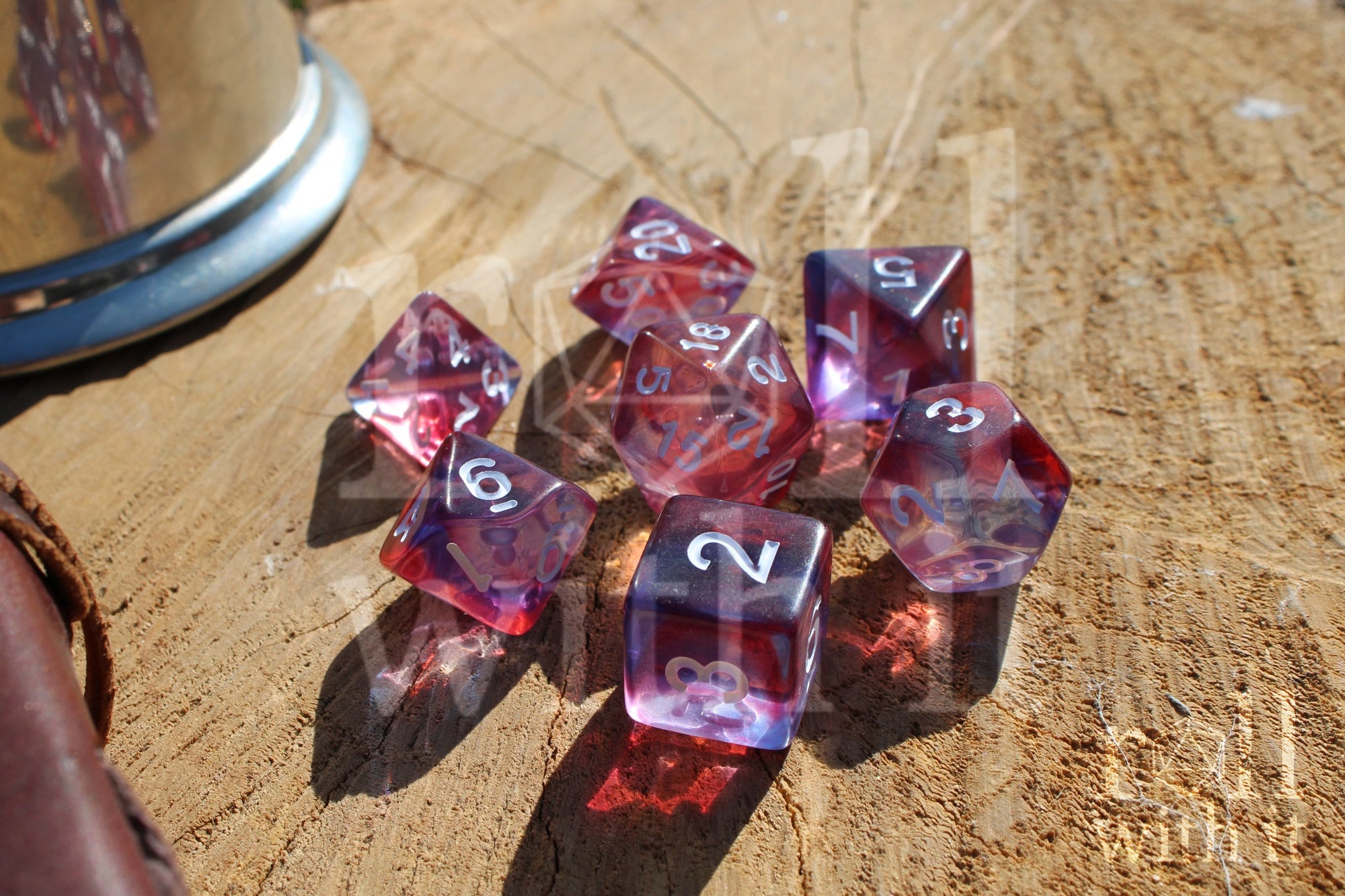 Set of clear purple and red polyhedral roleplaying dice with white numbers on a wooden surface