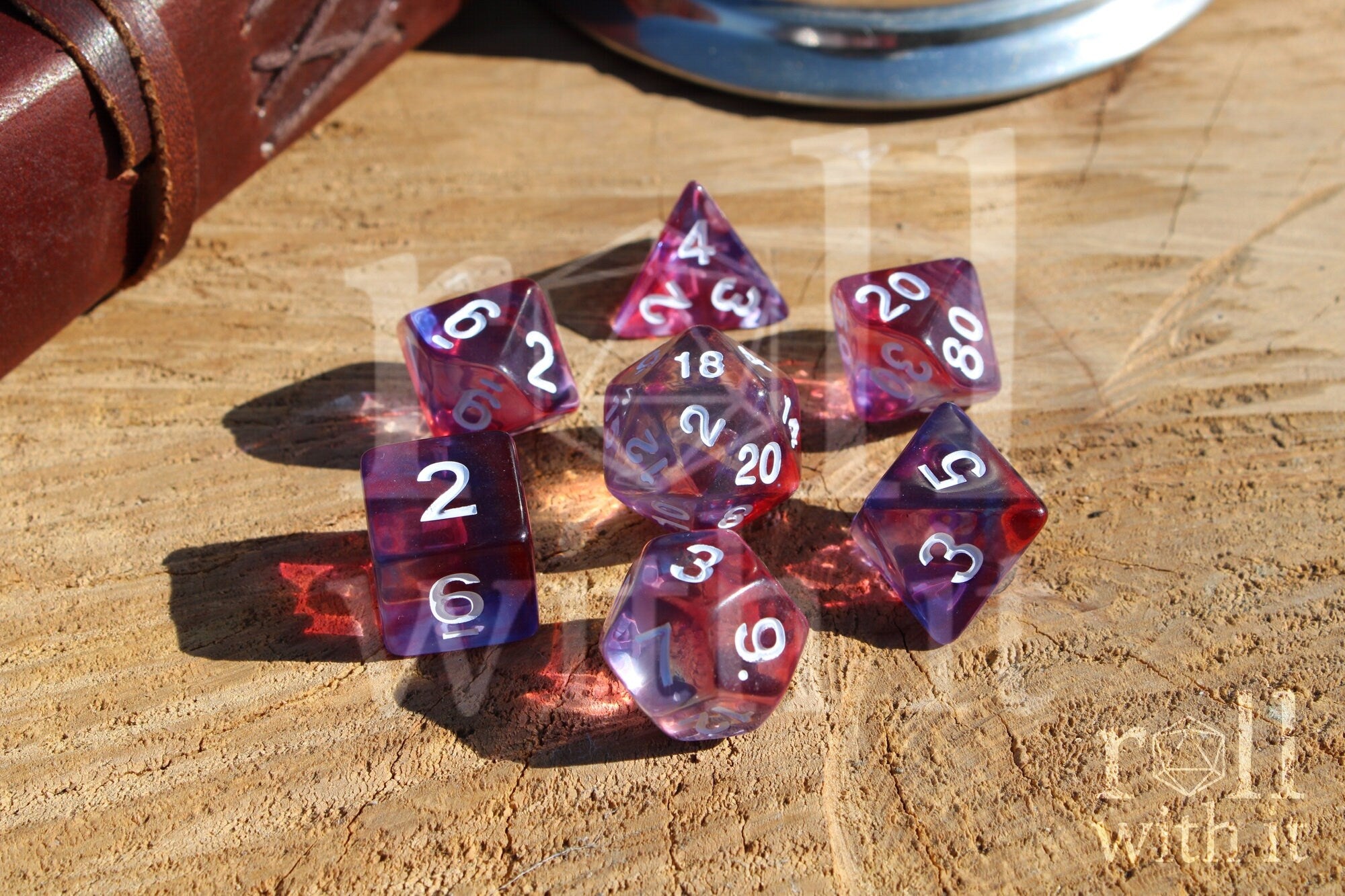 Set of clear purple and red polyhedral roleplaying dice with white numbers on a wooden surface