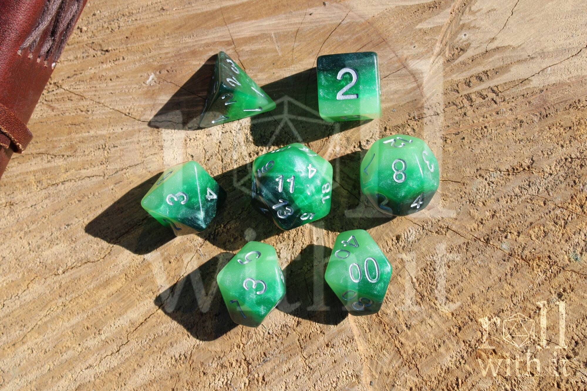 Green and black glittery polyhedral roleplaying dice set on a wooden surface