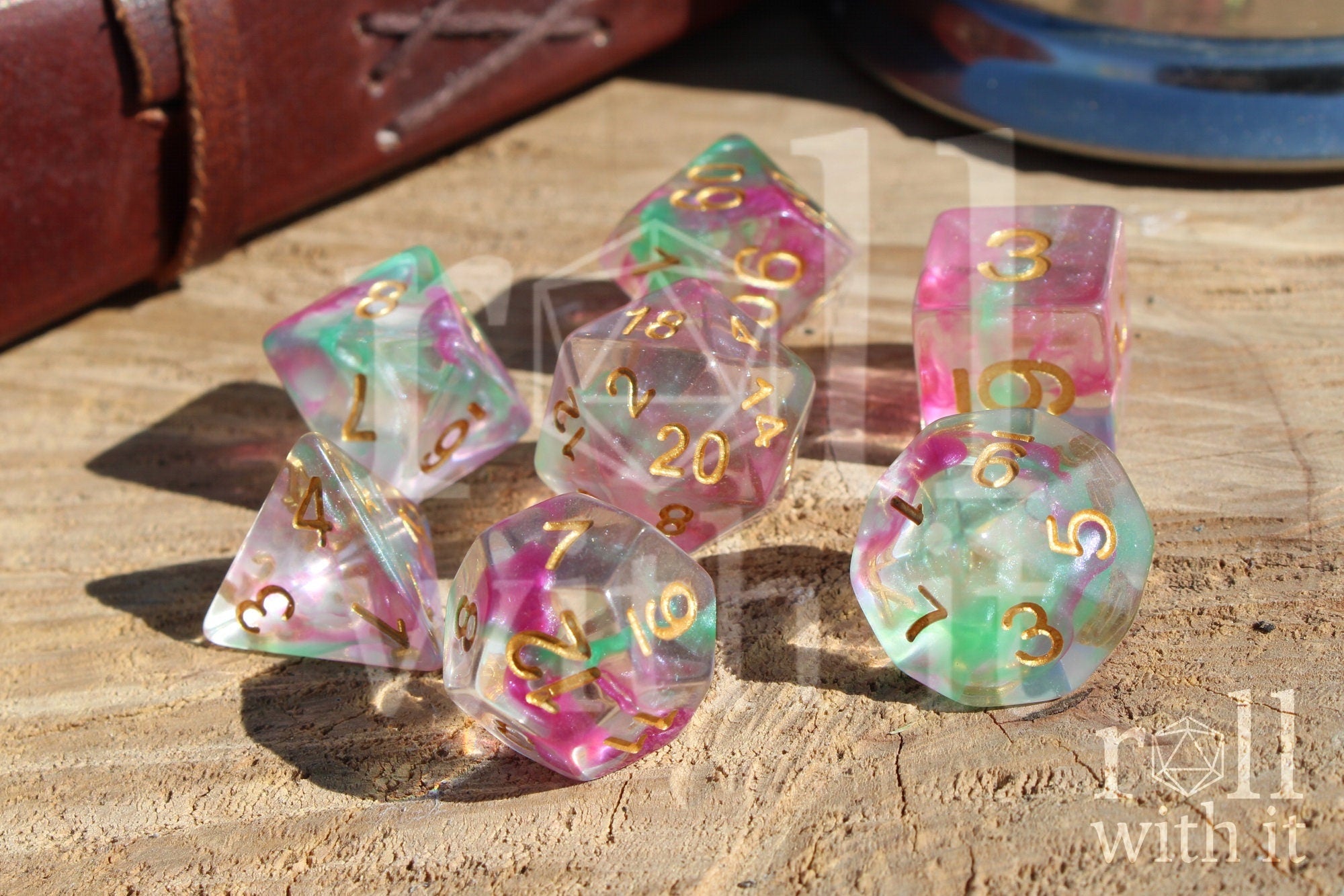 Set of purple and green clear dice with gold numbers on a wooden surface