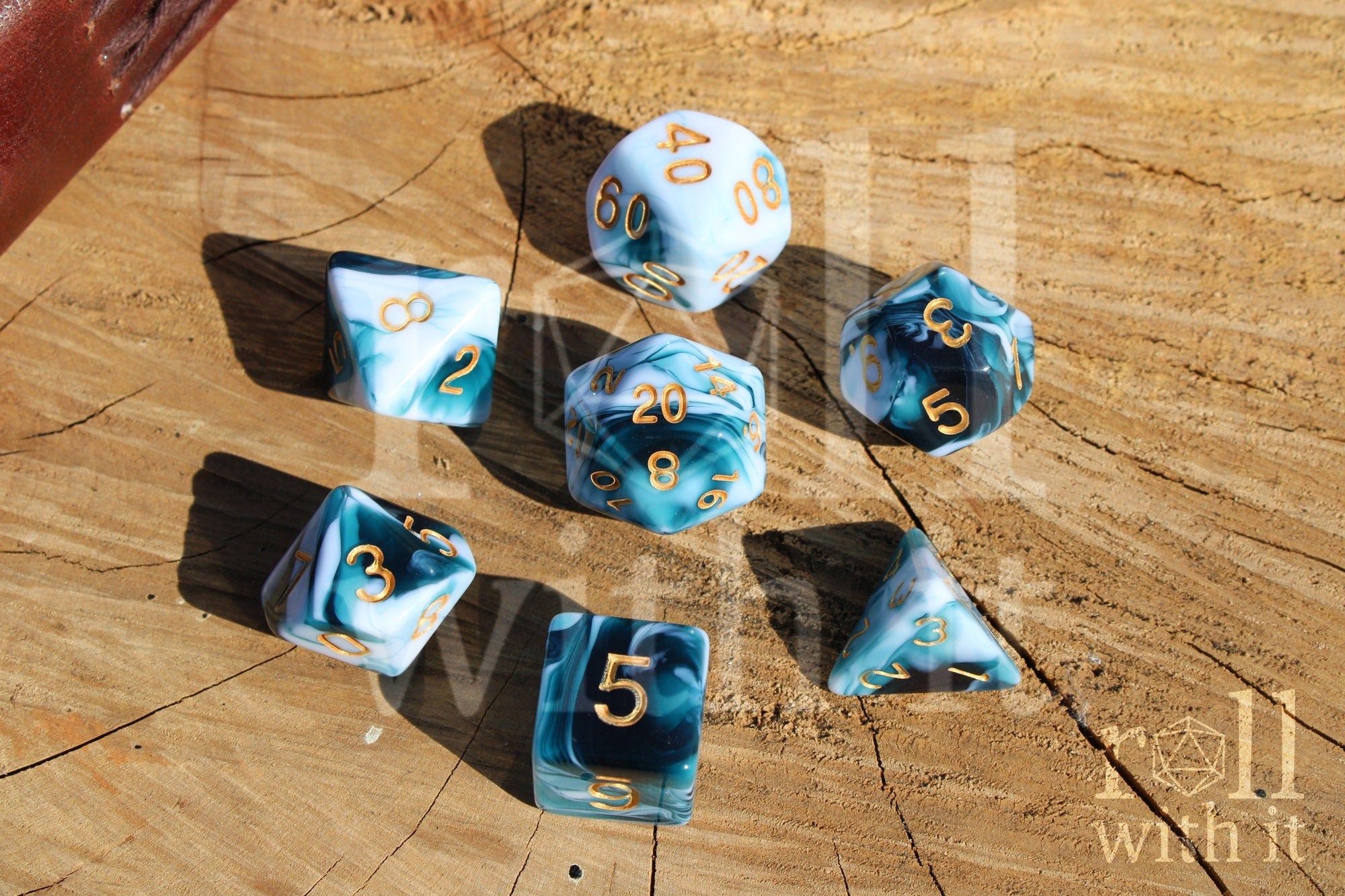 Set of blue and white marble polyhedral roleplaying dice with gold numbers on a wooden surface.