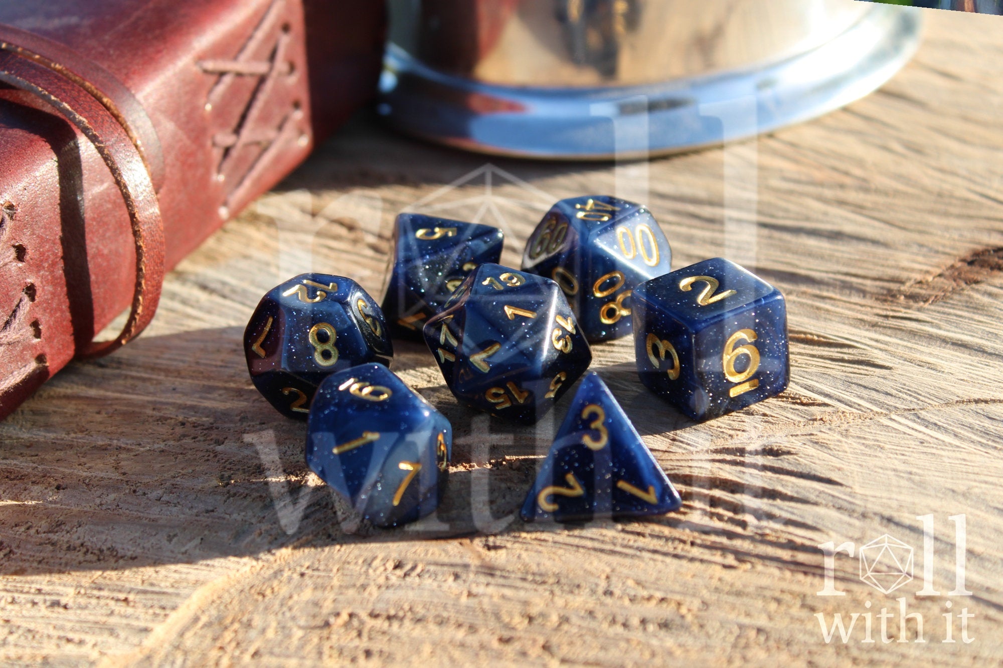 Deep midnight blue polyhedral starry glittery roleplaying dice with gold numbers on a wooden surface