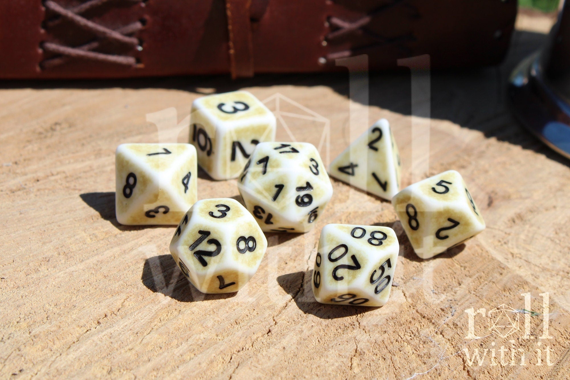 Set of creamy bone white matte dice with black numbers on a wooden surface