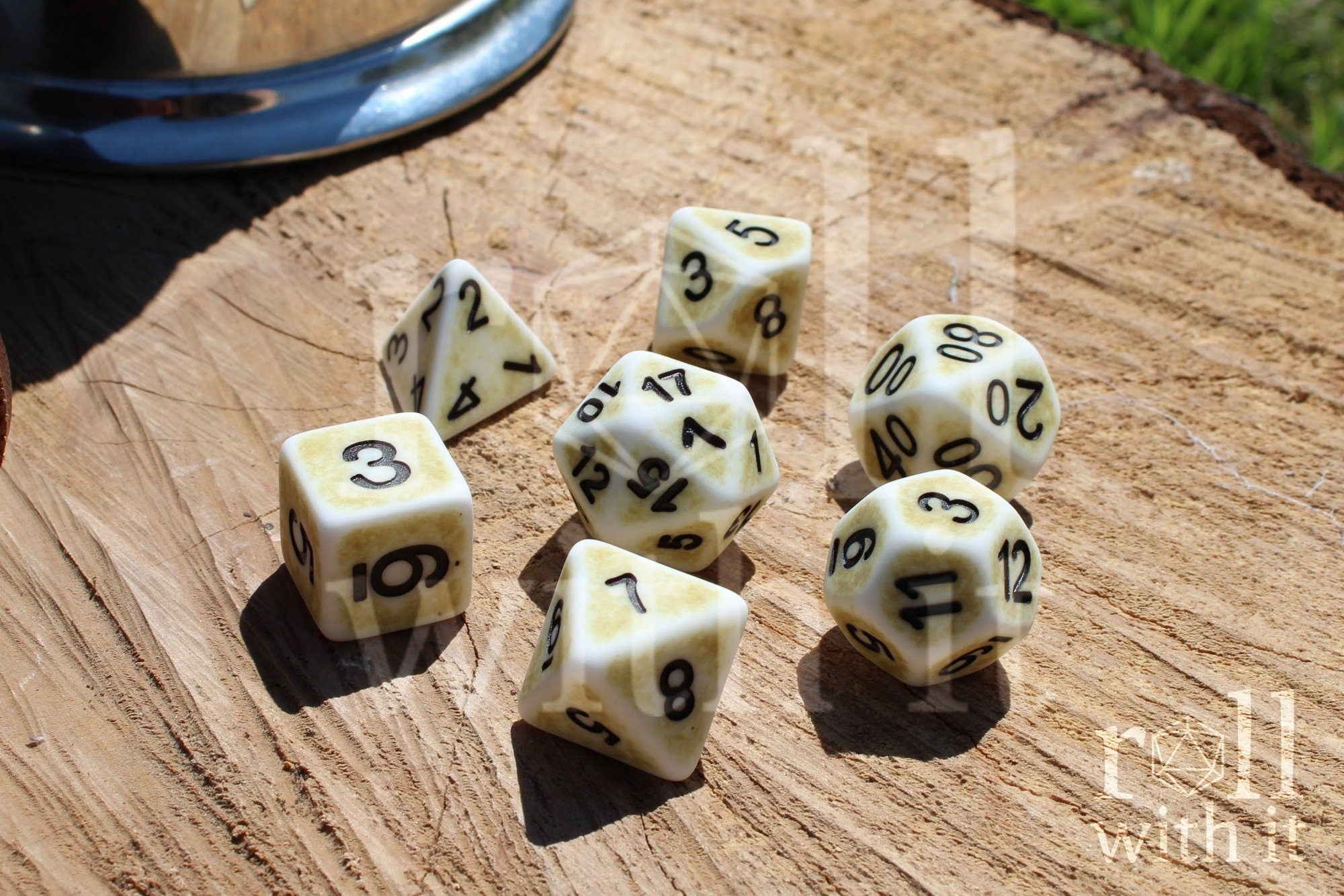 Set of creamy bone white matte roleplaying dice with black numbers on a wooden surface