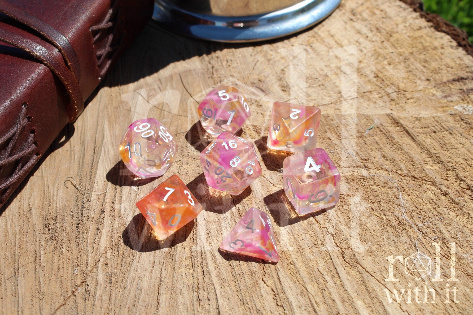 Set of colorful pink and orange clear polyhedral dice on a wooden surface