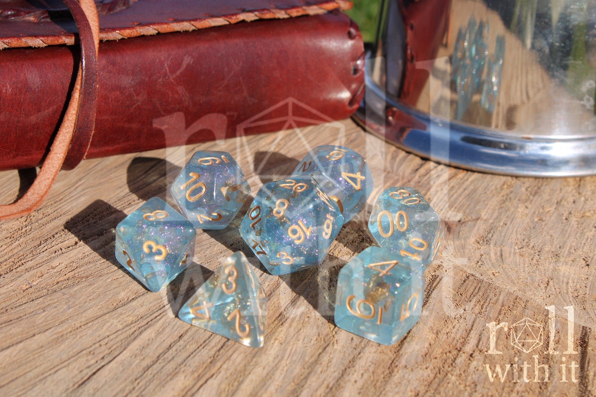 Set of clear blue and gold foil dice with gold numbers on a wooden surface
