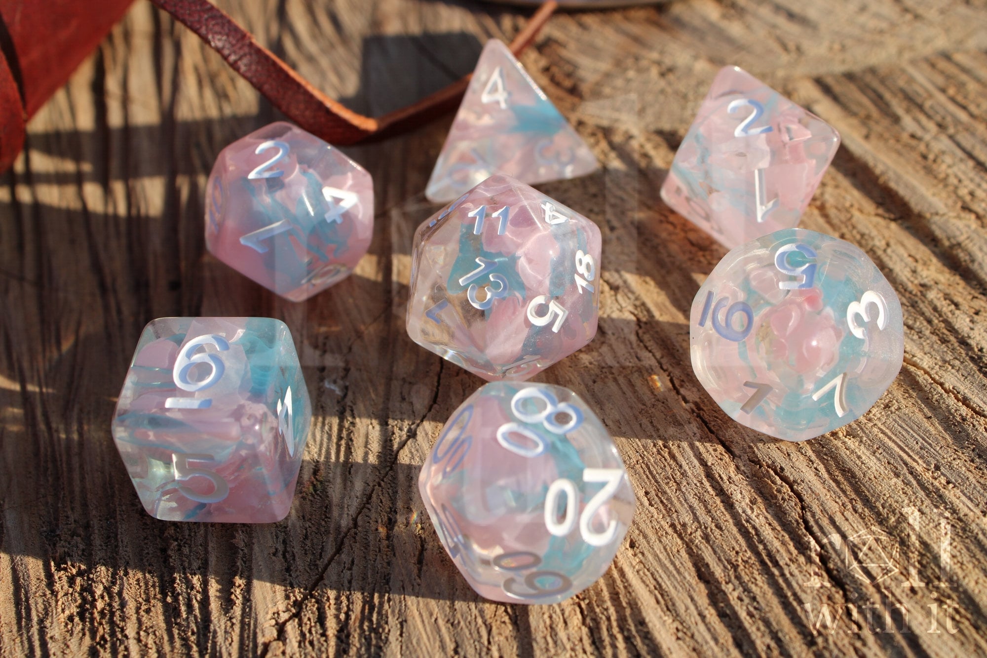 Set of pink and pale blue translucent polyhedral roleplaying dice on a wooden surface