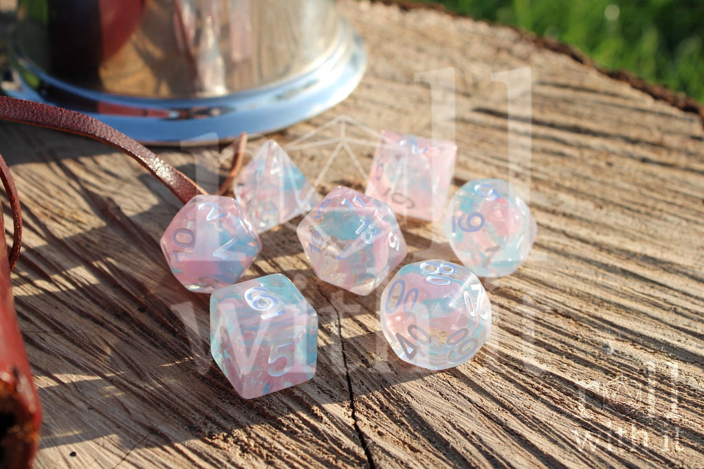 Set of pink and pale blue translucent polyhedral DND dice on a wooden surface