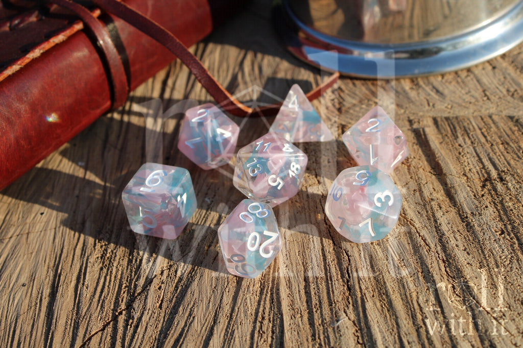 Set of pink and pale blue translucent polyhedral DND dice on a wooden surface