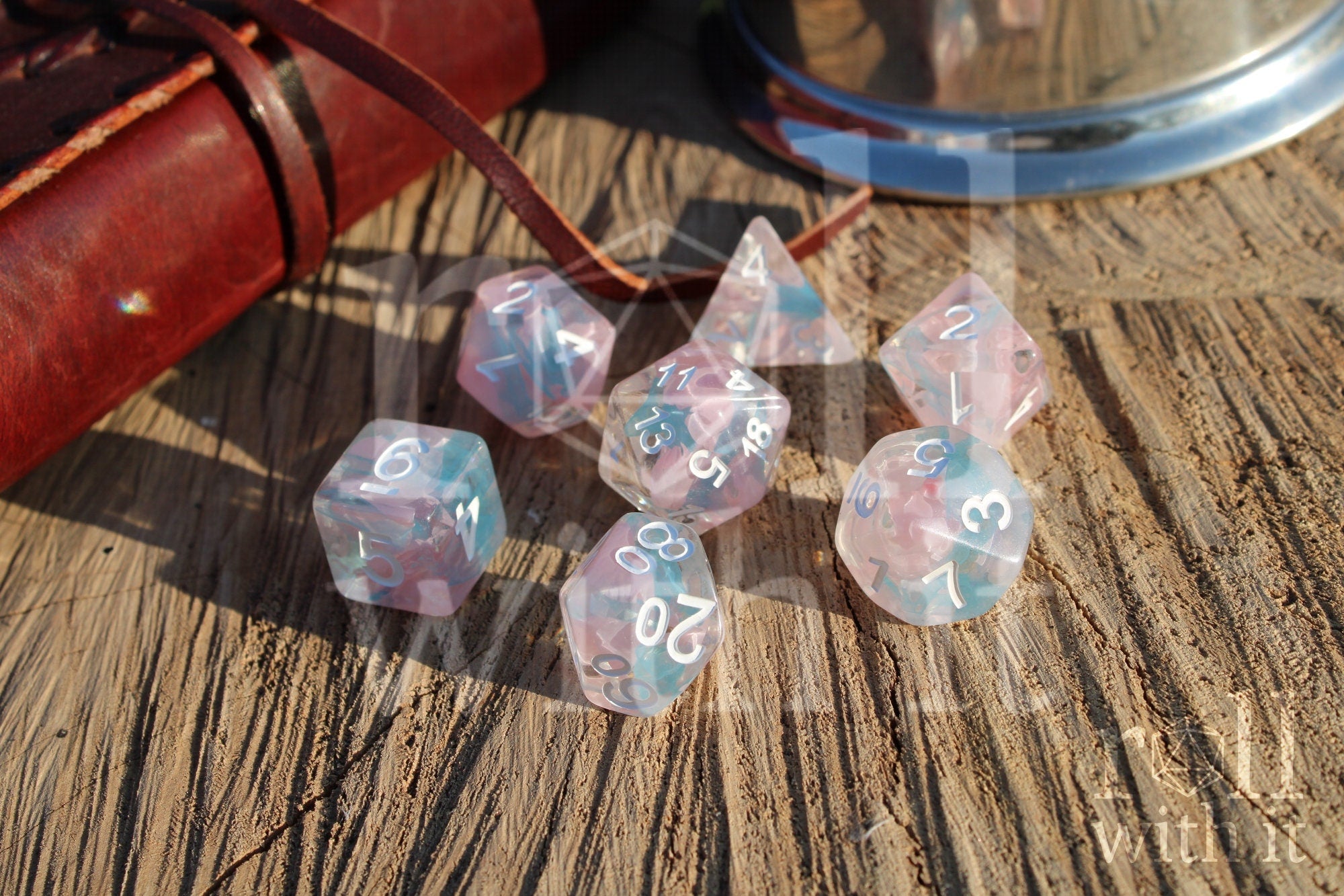 Set of pink and pale blue translucent polyhedral DND dice on a wooden surface