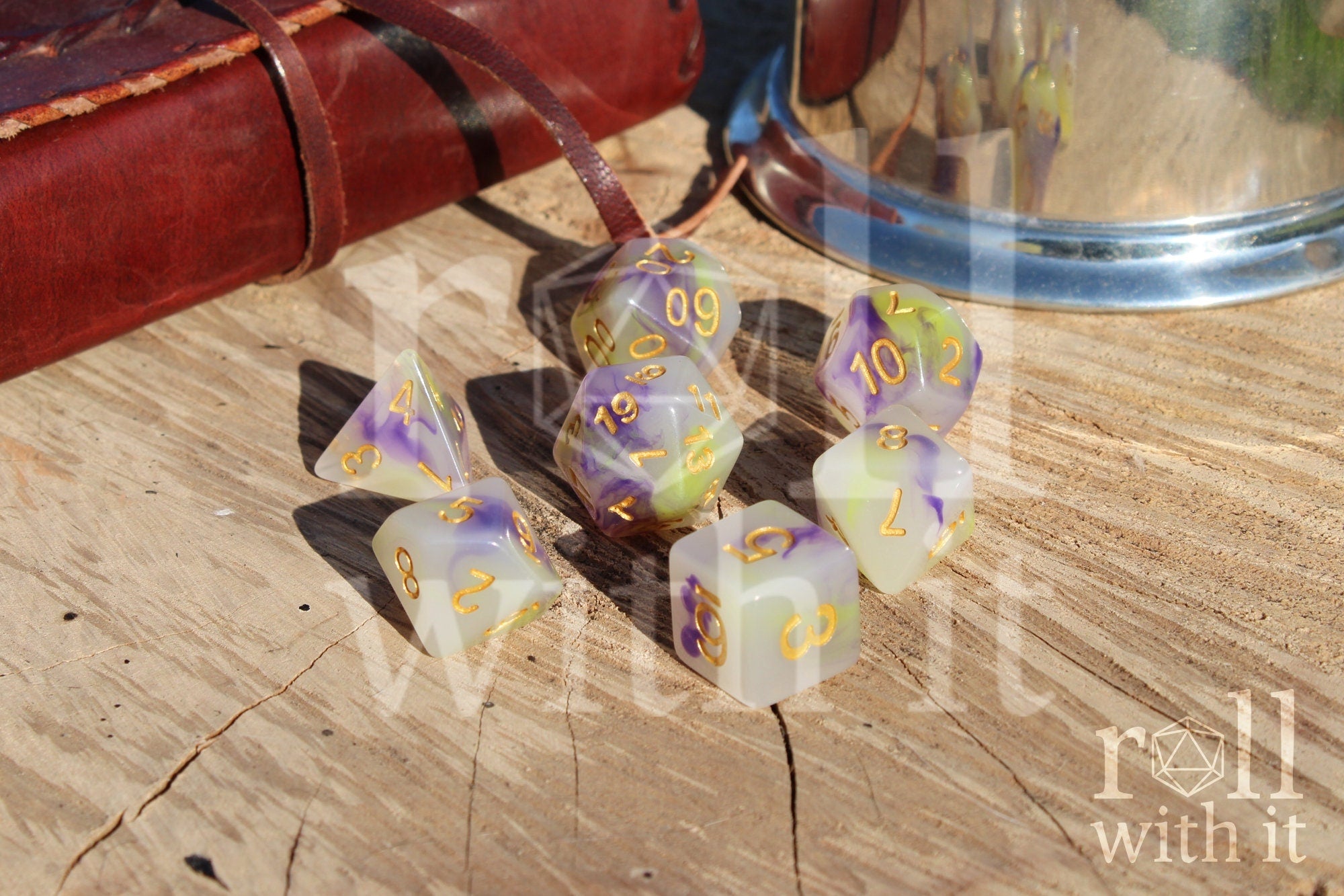 Set of purple green and creamy white dice with gold numbers on a wooden surface