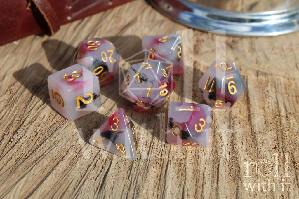 Set of black, red, and creamy white role playing dice with marbled design and gold numbers on a wooden surface