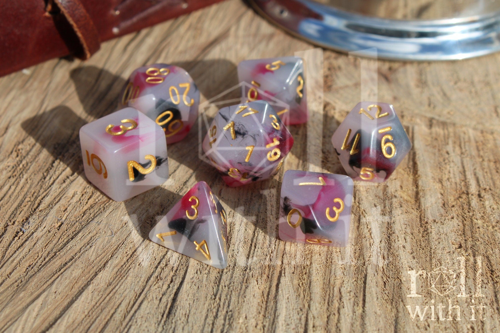 Set of black, red, and creamy white role playing dice with marbled design and gold numbers on a wooden surface