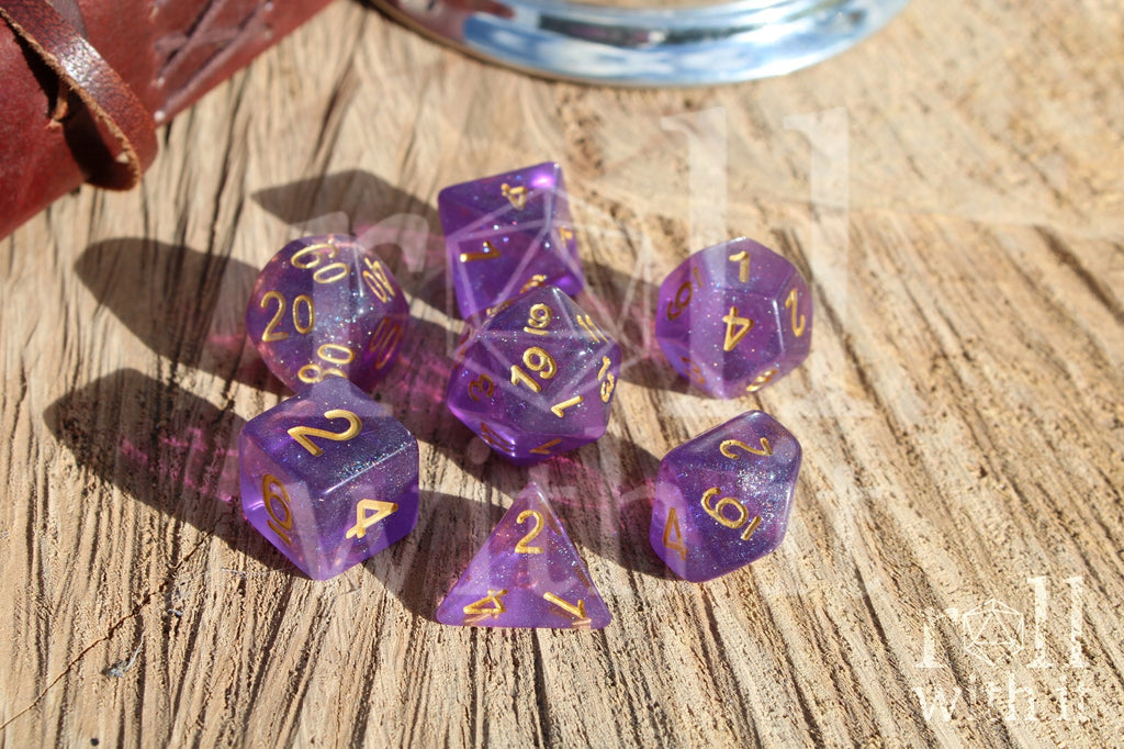 Set of glittery purple polyhedral DnD dice with gold numbers on a wooden surface
