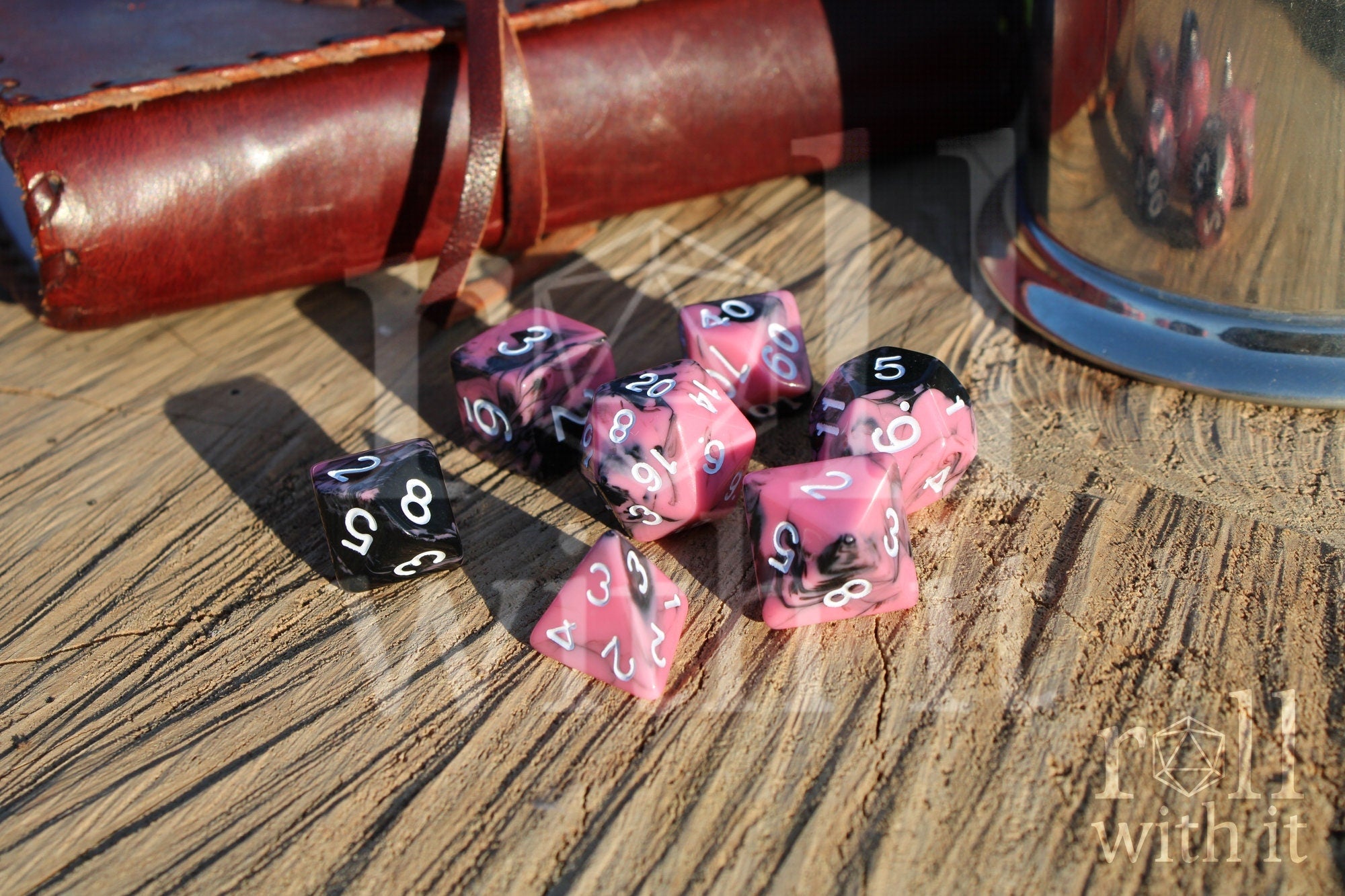 Set of pink and black polyhedral dice on a wooden surface