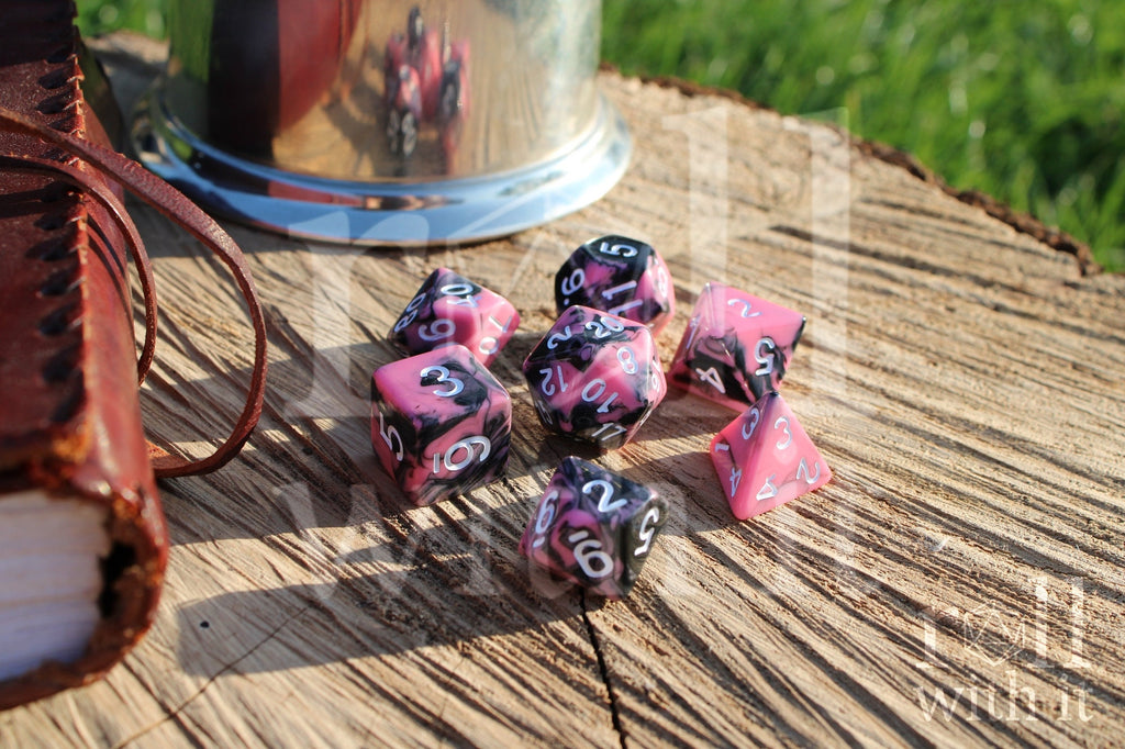 Set of pink and black polyhedral dice on a wooden surface