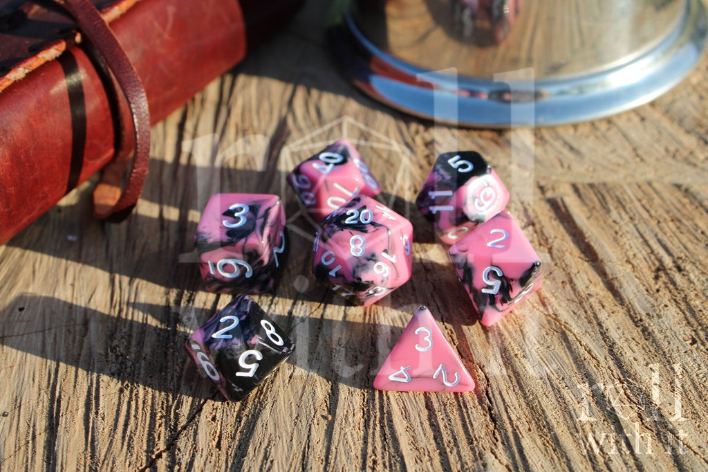 Set of pink and black polyhedral dice on a wooden surface