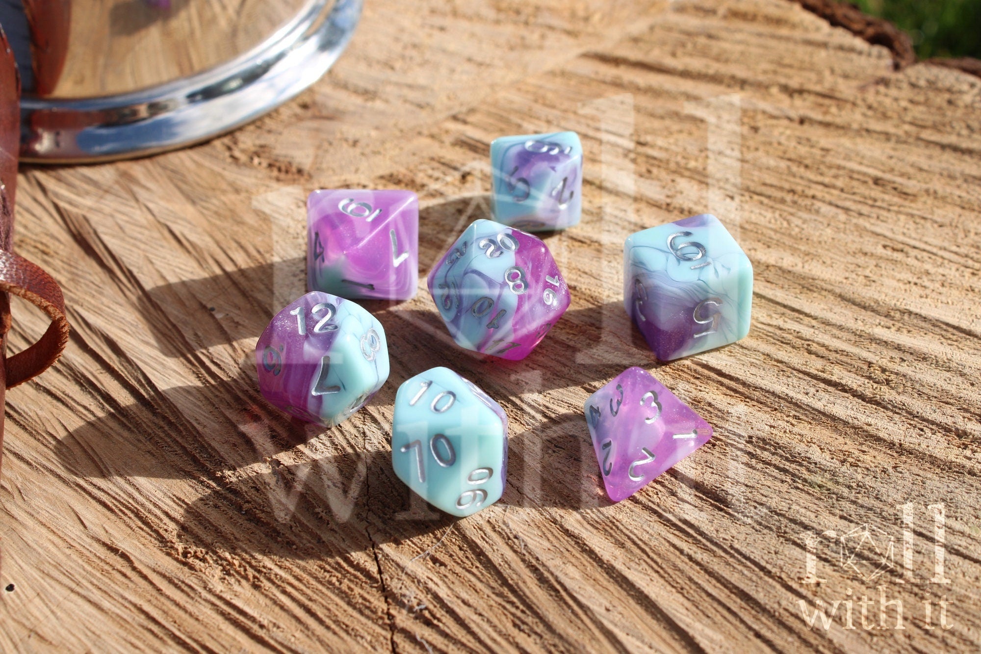 Set of 7 pastel blue marble and clear orchid purple polyhedral DND roleplaying dice on a wooden surface