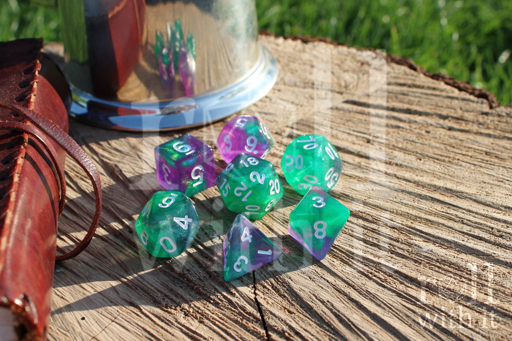 Set of colorful and glittery green and purple polyhedral dice on a wooden surface