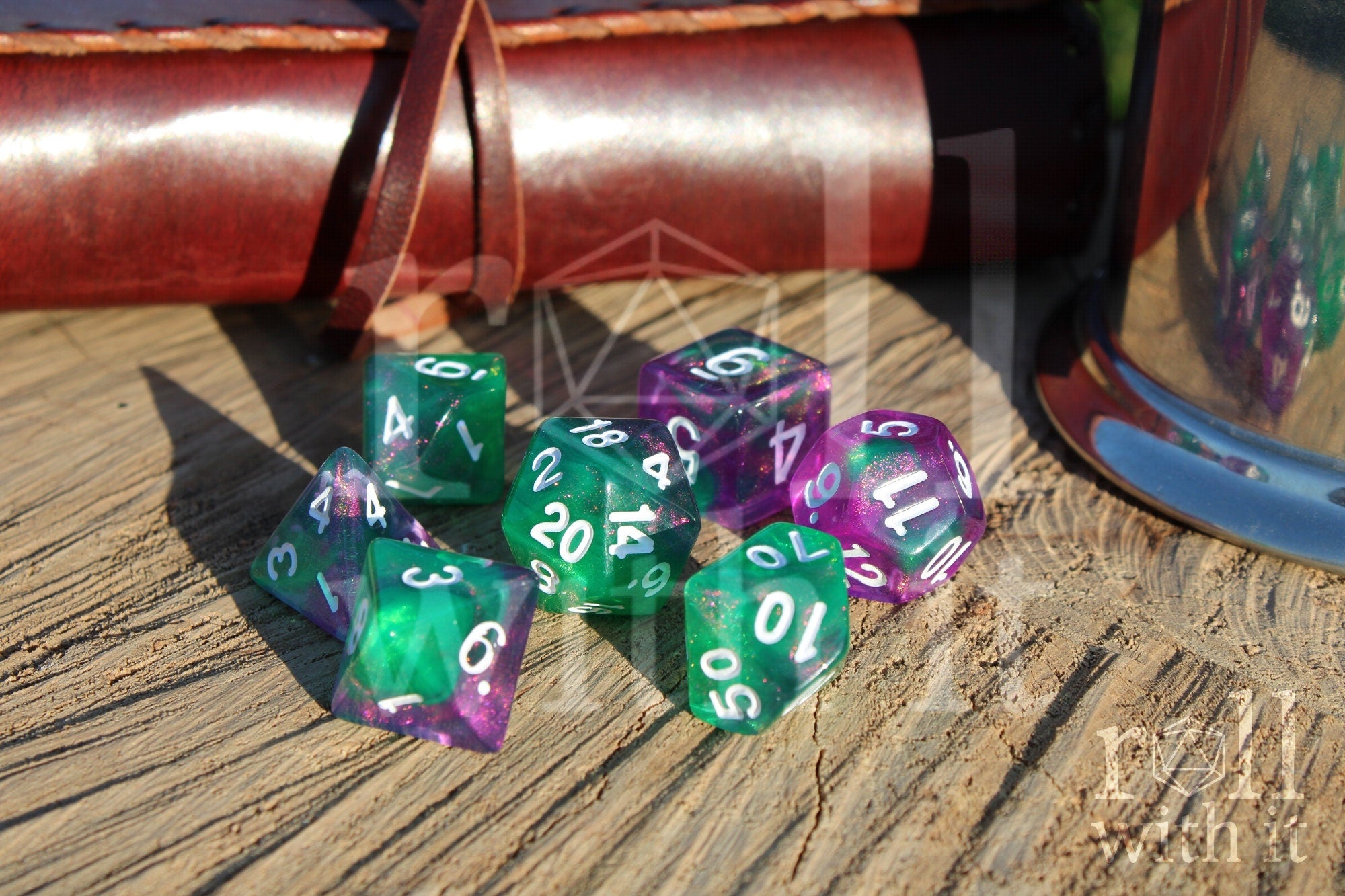 Set of colorful and glittery green and purple polyhedral dice on a wooden surface