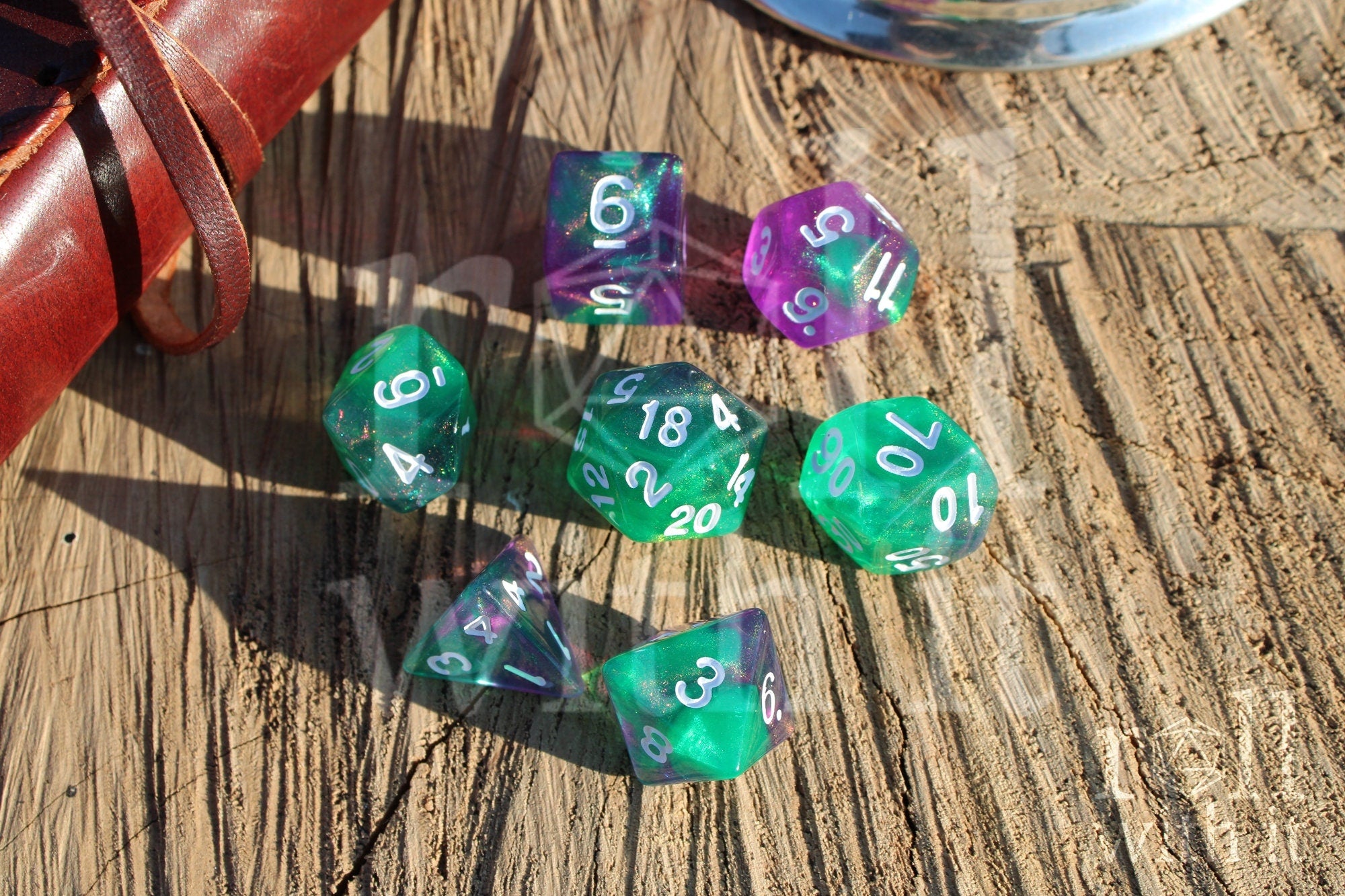 Set of colorful and glittery green and purple polyhedral dice on a wooden surface