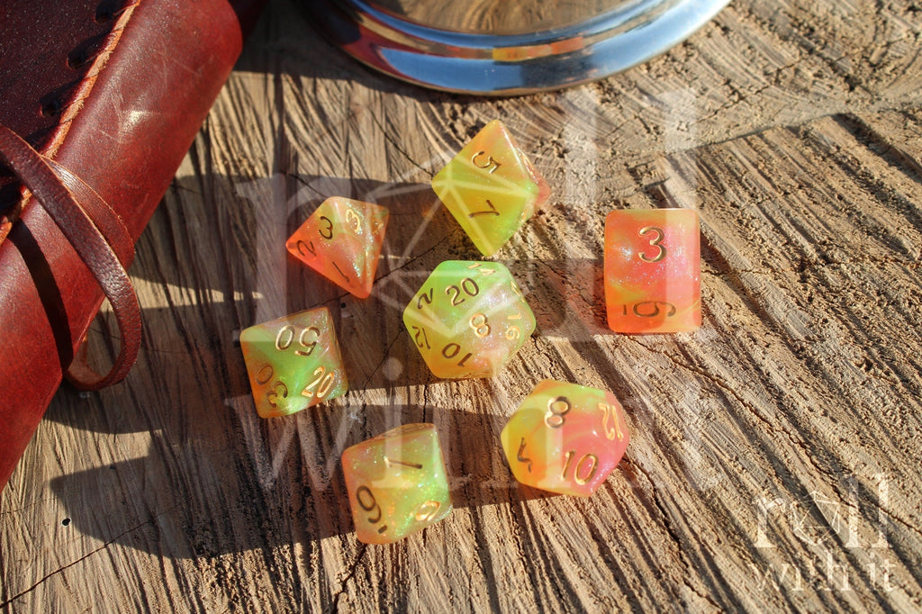 Set of colourful glittery light green and peachy pink polyhedral dice on a wooden surface