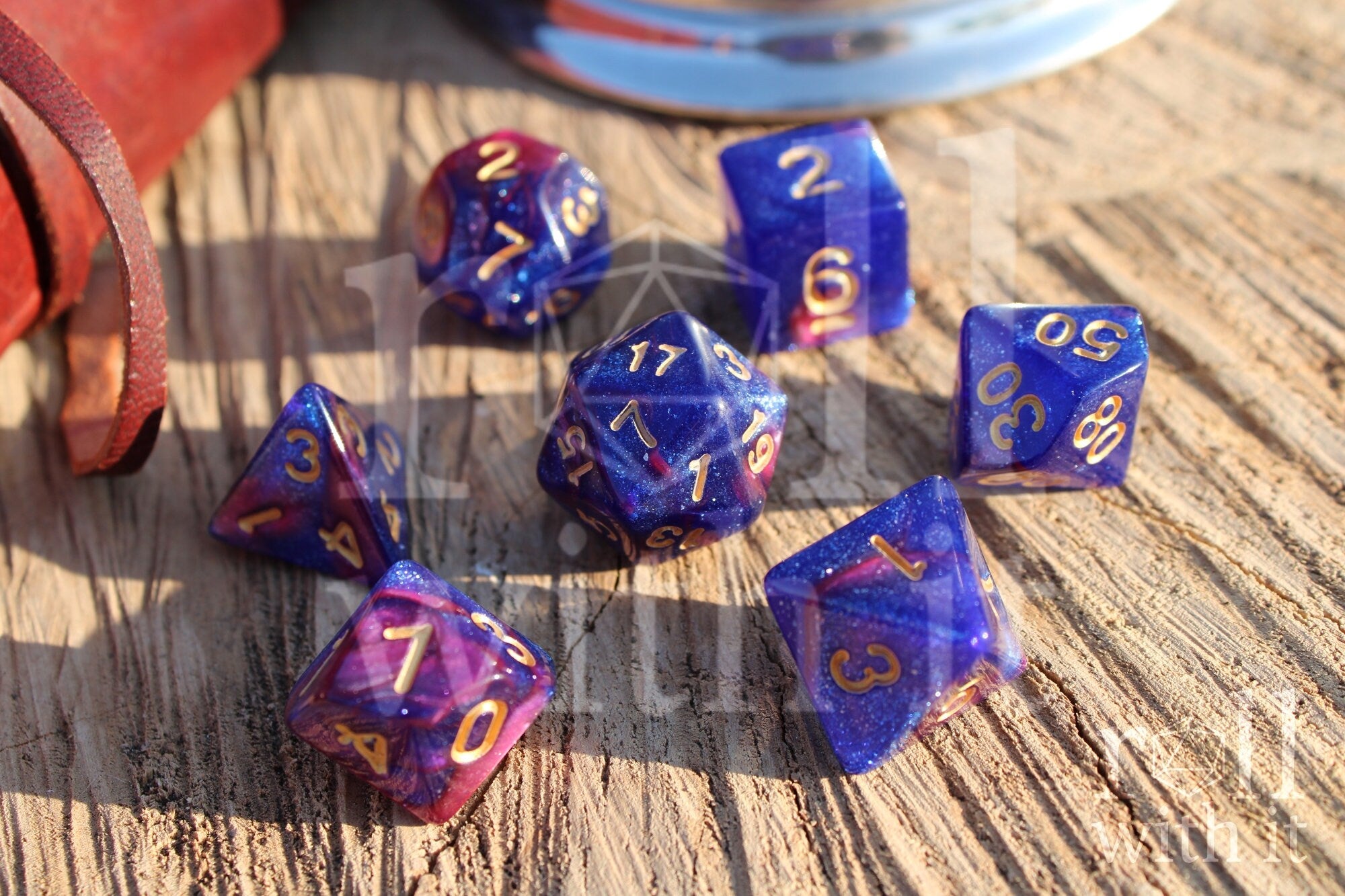 Set of purple and blue polyhedral dice with gold numbers on a wooden surface