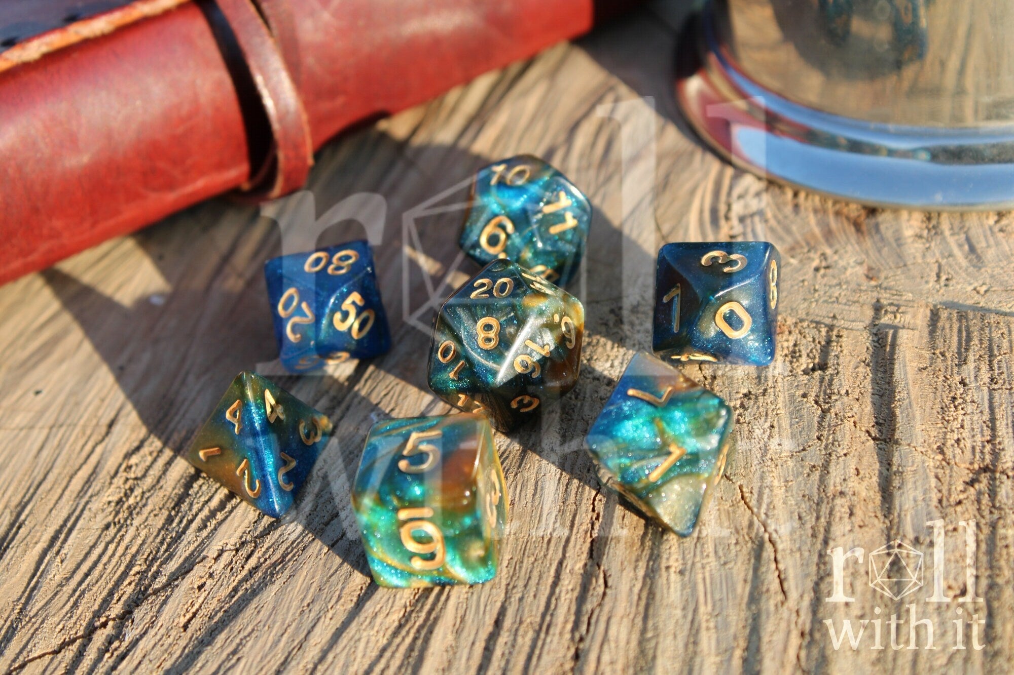 Set of glittery mixed blue, green, and gold polyhedral roleplaying dice on a wooden surface