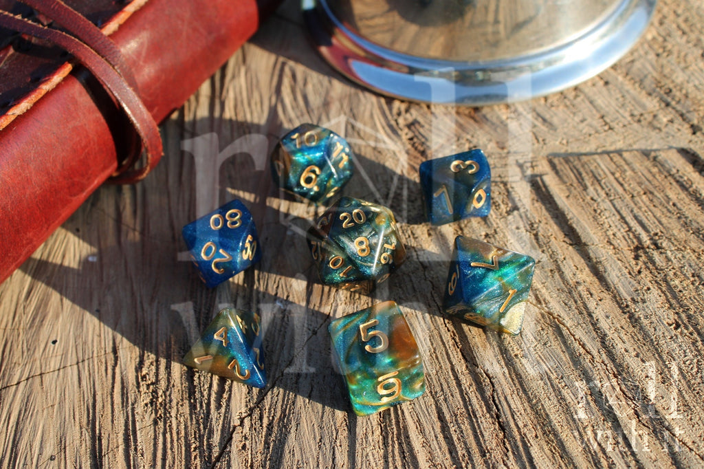 Set of glittery mixed blue, green, and gold polyhedral roleplaying dice on a wooden surface