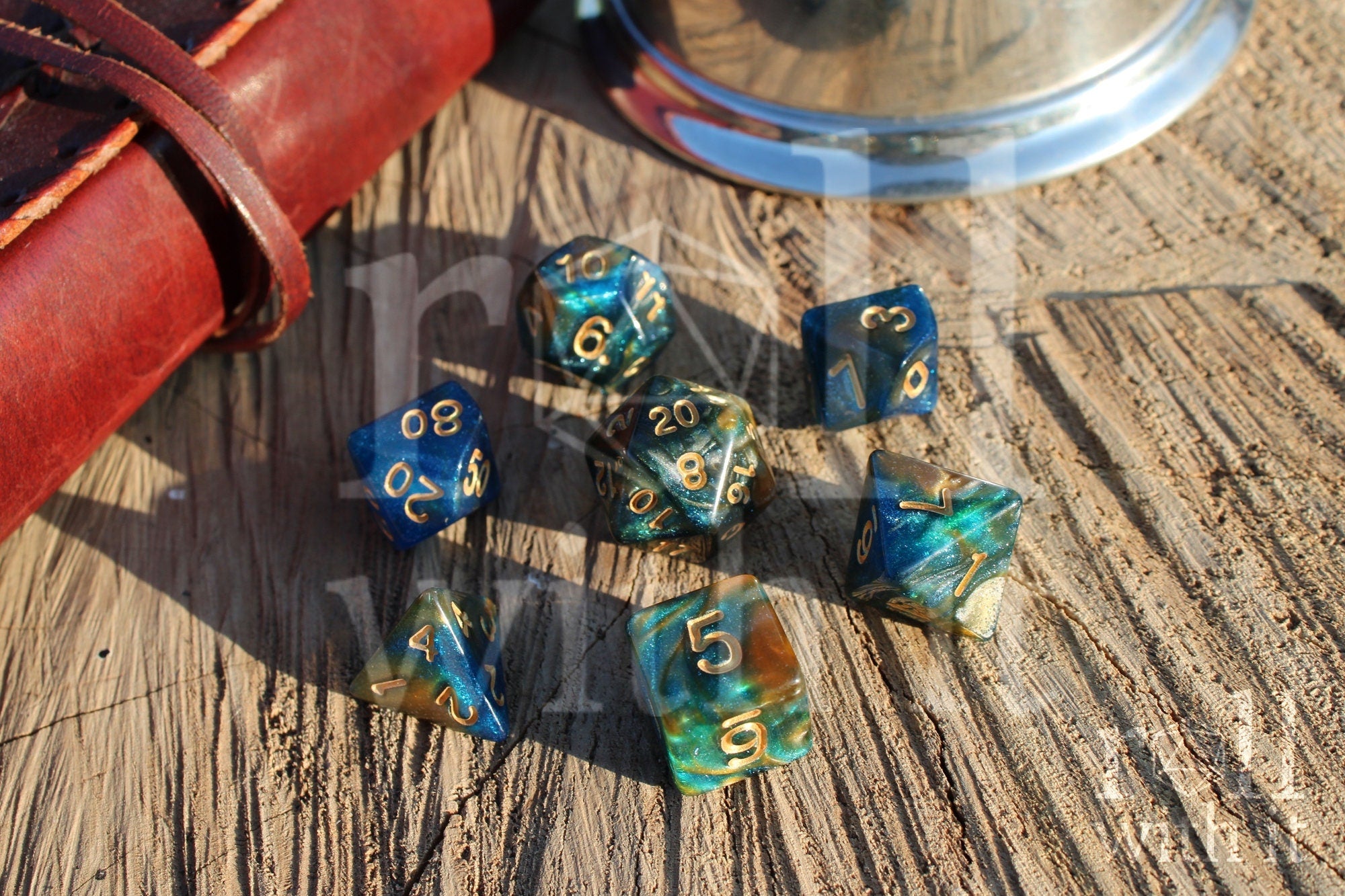 Set of glittery mixed blue, green, and gold polyhedral roleplaying dice on a wooden surface