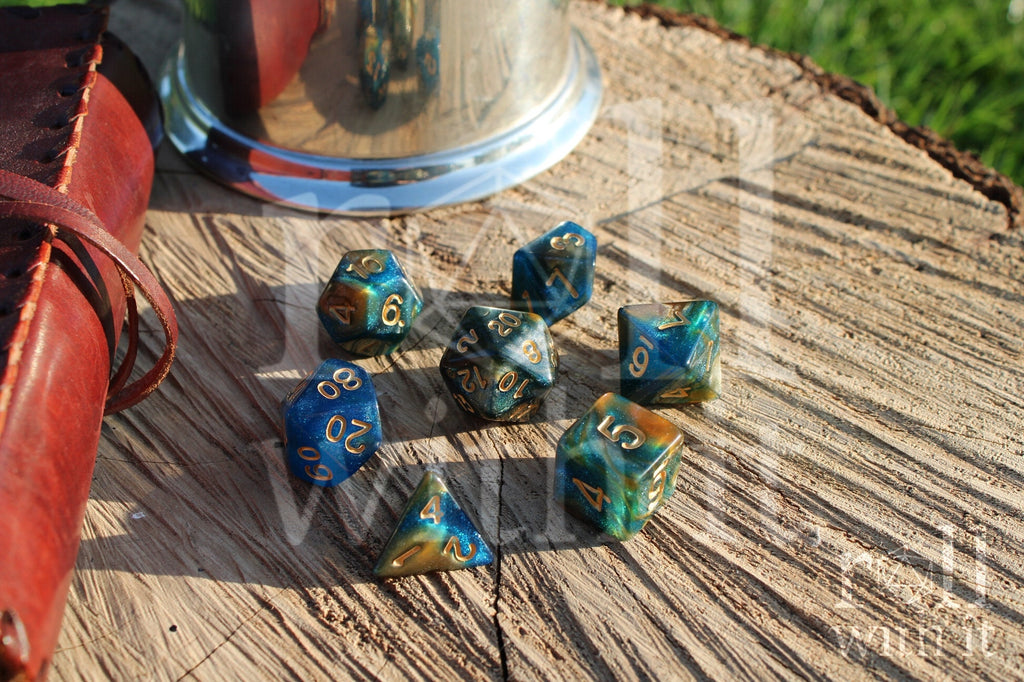 Set of glittery mixed blue, green, and gold polyhedral dice on a wooden surface