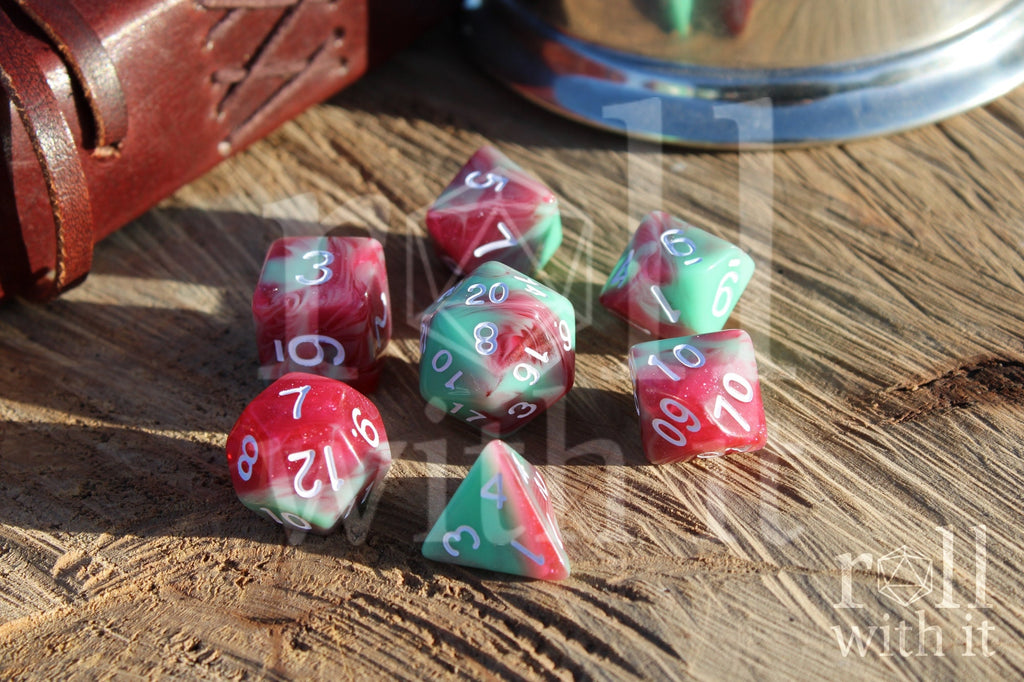 Set of glittery red and pastel green polyhedral roleplaying dice on a wooden surface