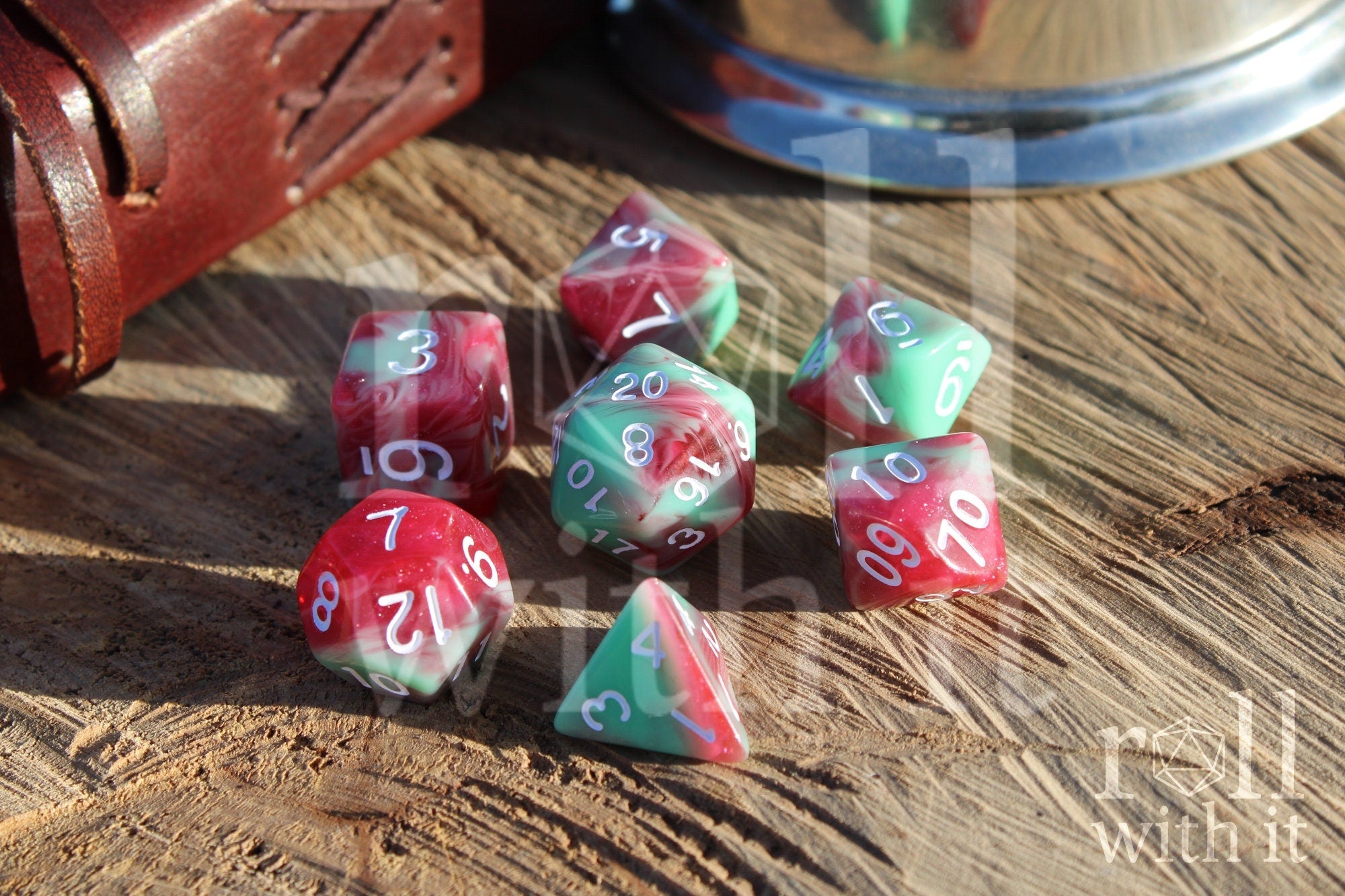 Set of glittery red and pastel green polyhedral roleplaying dice on a wooden surface