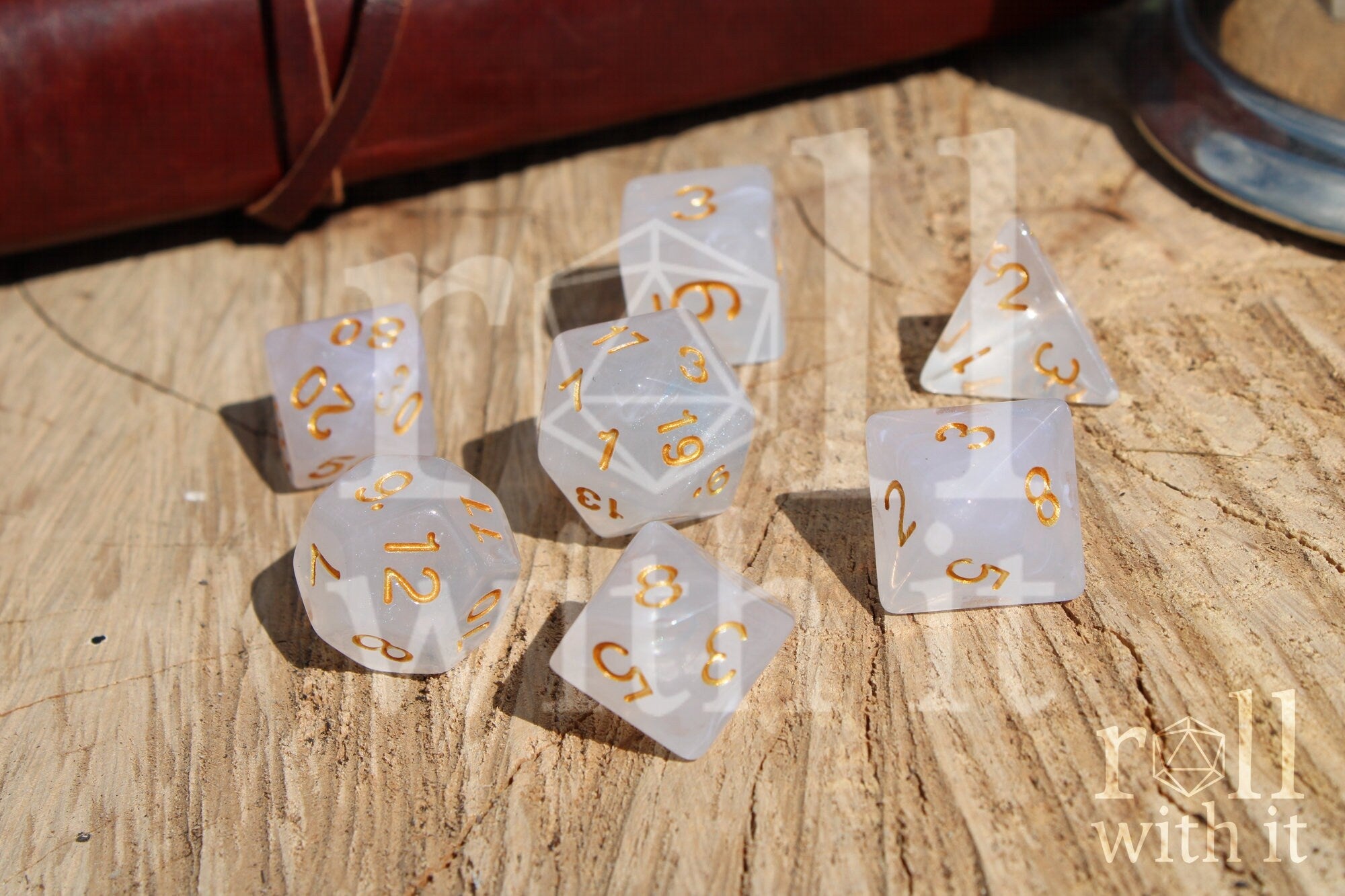 A set of polyhedral grey and silver dice with gold numbers on a wooden 