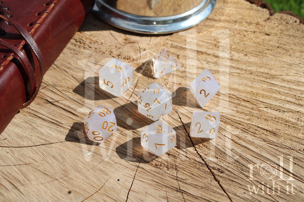 A set of polyhedral grey and silver dice with gold numbers on a wooden 