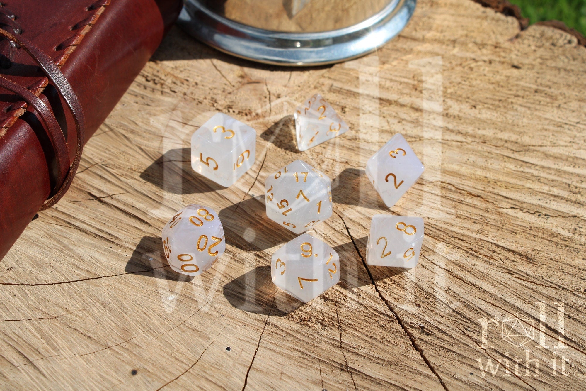 A set of polyhedral grey and silver dice with gold numbers on a wooden 