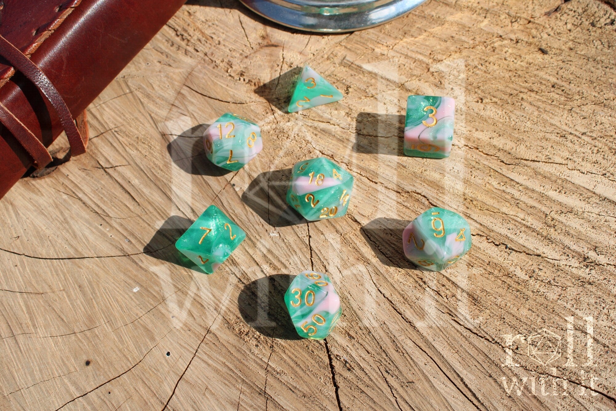 Set of colorful glittery teal green and pink polyhedral dice on a wooden surface