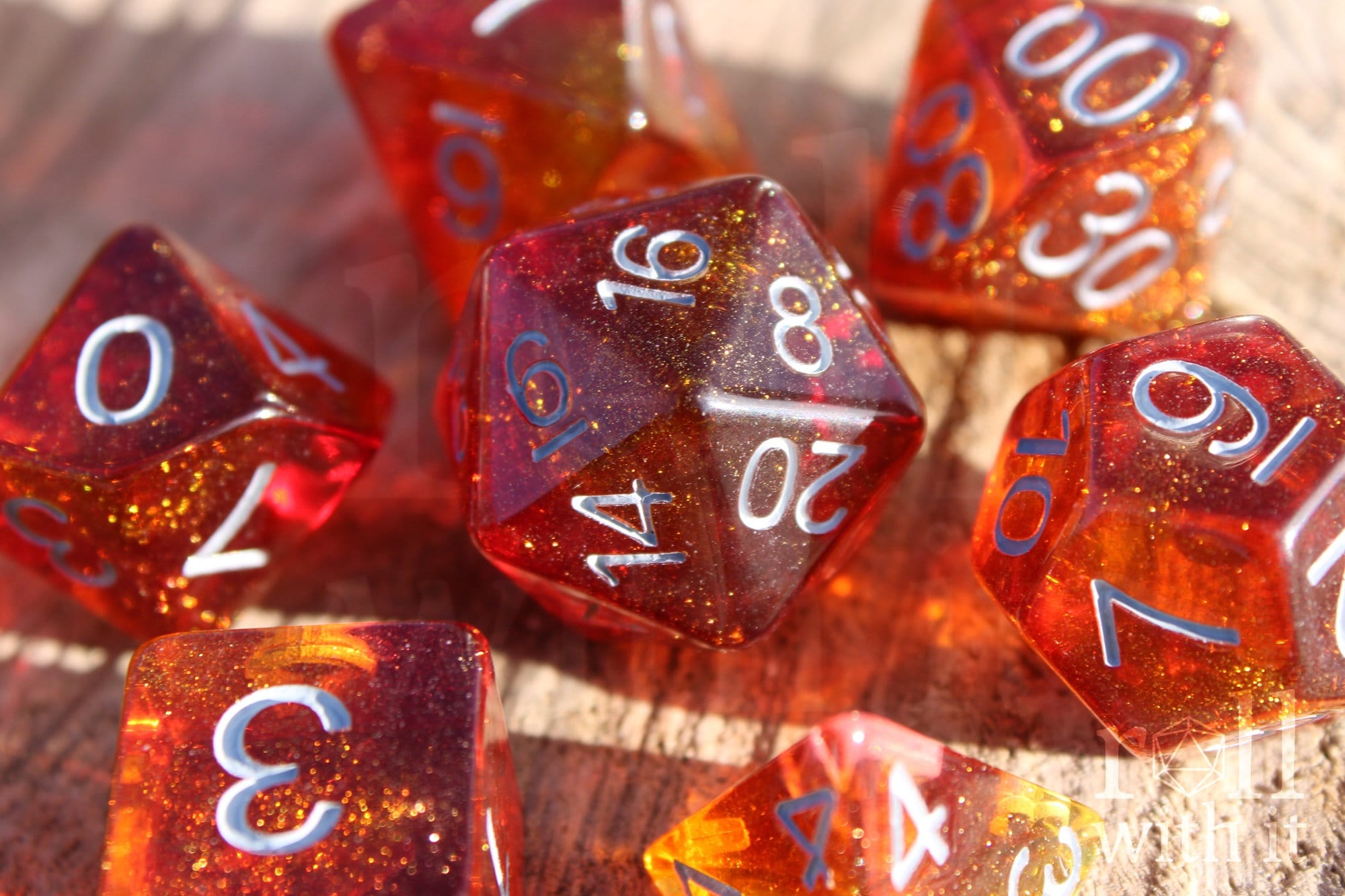 Set of vibrant and glittery red and orange polyhedral roleplaying dice with white numbers on a wooden surface