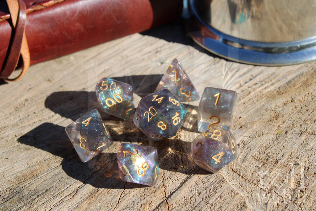 Set of iridescent glittery and star like DnD roleplaying dice with gold numbers and golden cogs inside on a wooden surface