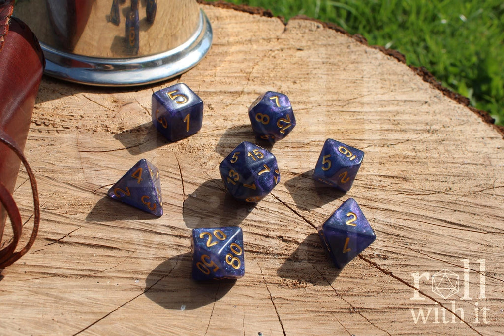 Deep blue and glittery polyhedral roleplaying dice with gold numbers on a wooden surface