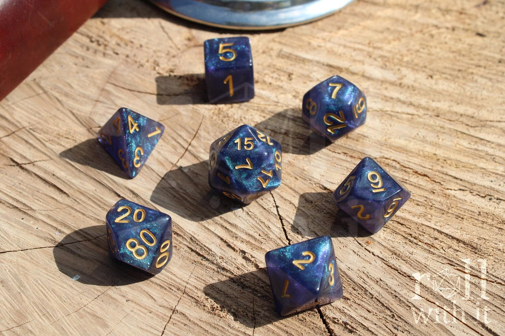 Blue glittery polyhedral dice with gold numbers on a wooden surface